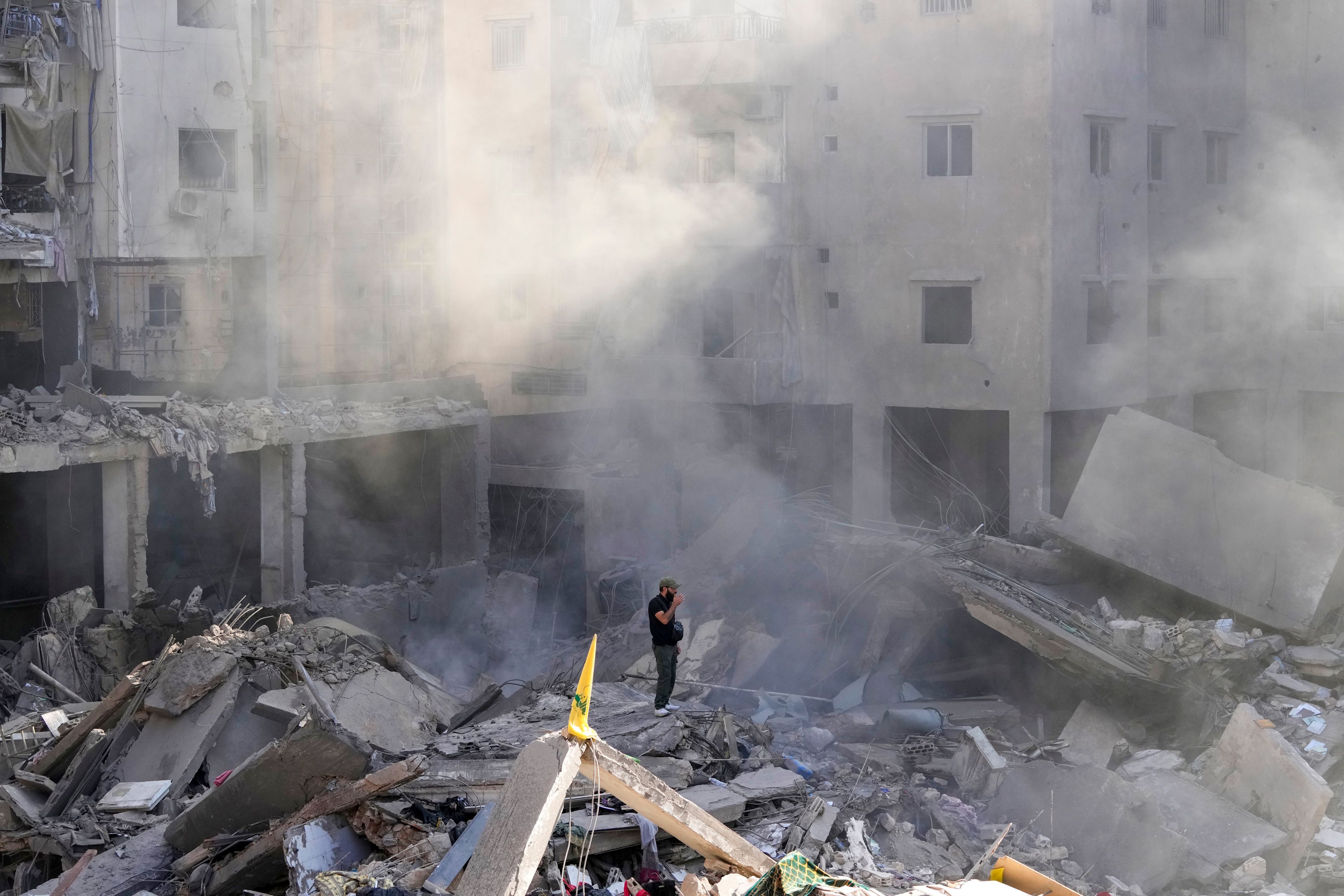 A man stands on the rubble of buildings near the site of the assassination of Hezbollah leader Hassan Nasrallah in Beirut's southern suburbs, Sunday, Sept. 29, 2024. (AP Photo/Hassan Ammar)