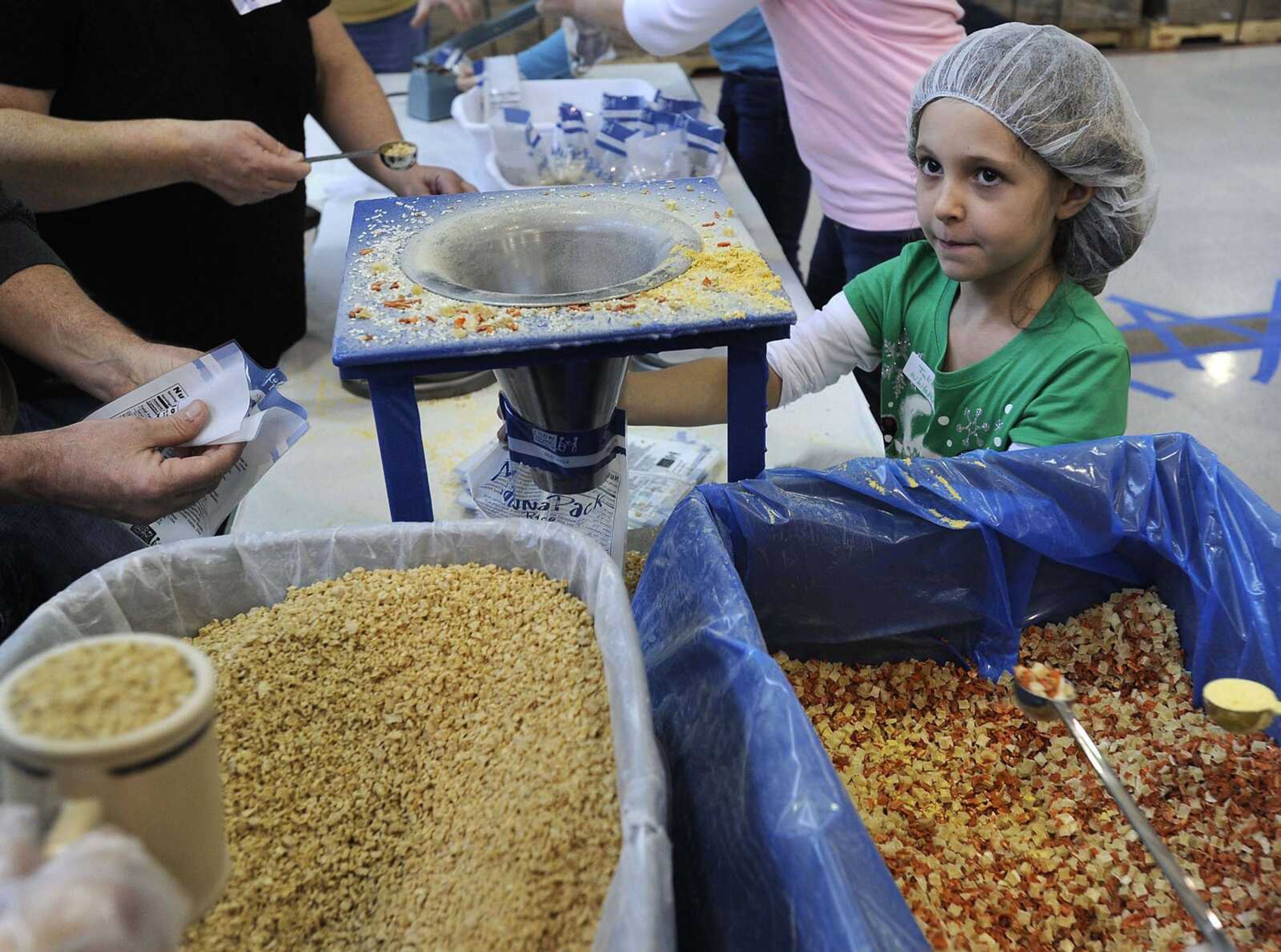 By line:Julia Whitaker holds a MannaPack rice bag for filling at the Feed My Starving Children MobilePack event Sunday, Dec. 7, 2014 at the Osage Centre in Cape Girardeau.