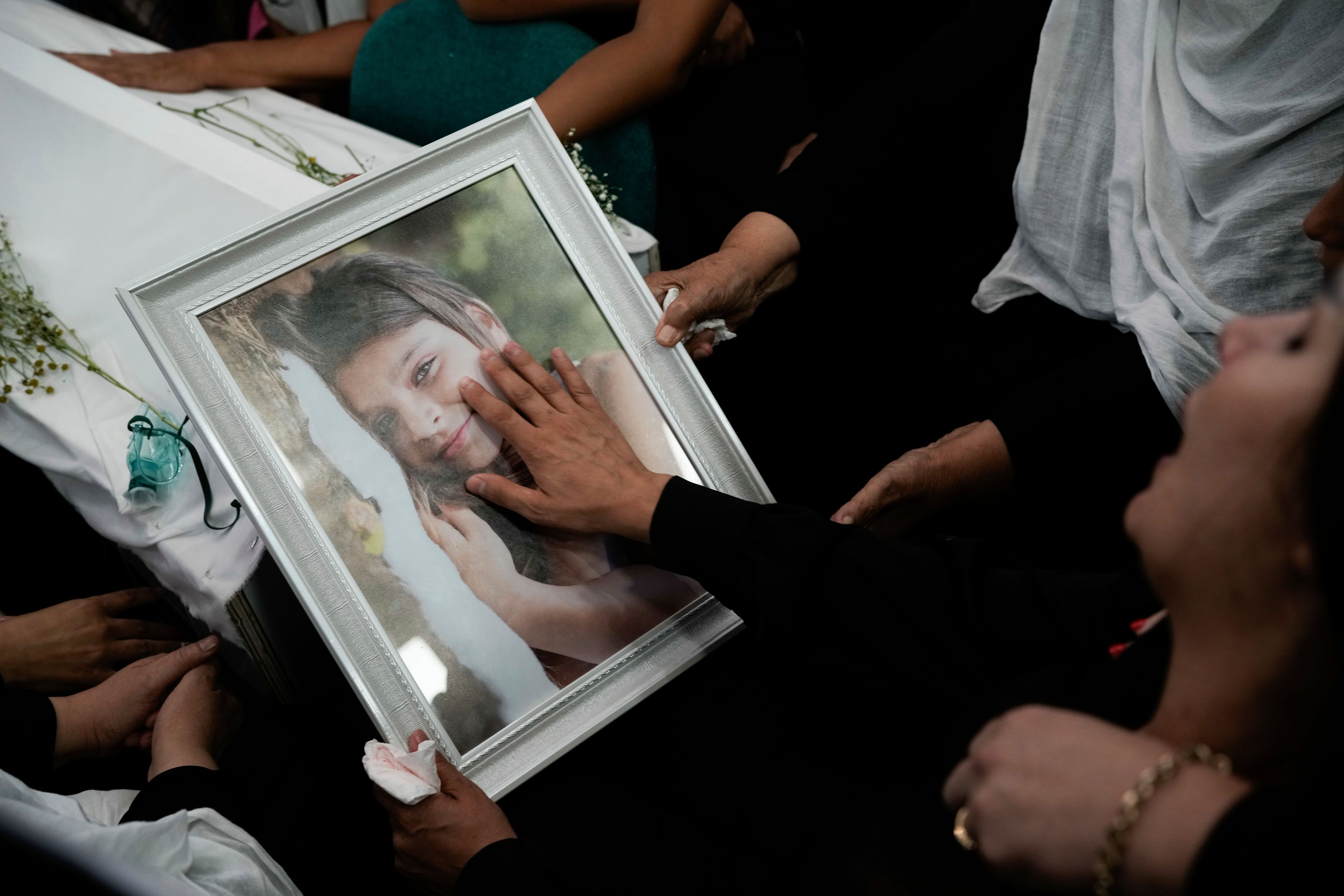 Members of the Druze minority place a photo of Alma Fkhrden, 12, on her coffin during her funeral at the village of Majdal Shams in the Israeli-controlled Golan Heights, Sunday, July 28, 2024. A rocket strike at a soccer field in the village has killed at least 11 children and teens. It's the deadliest strike on an Israeli target along the country's northern border since the fighting between Israel and the Lebanese militant group Hezbollah began. (AP Photo/Leo Correa)