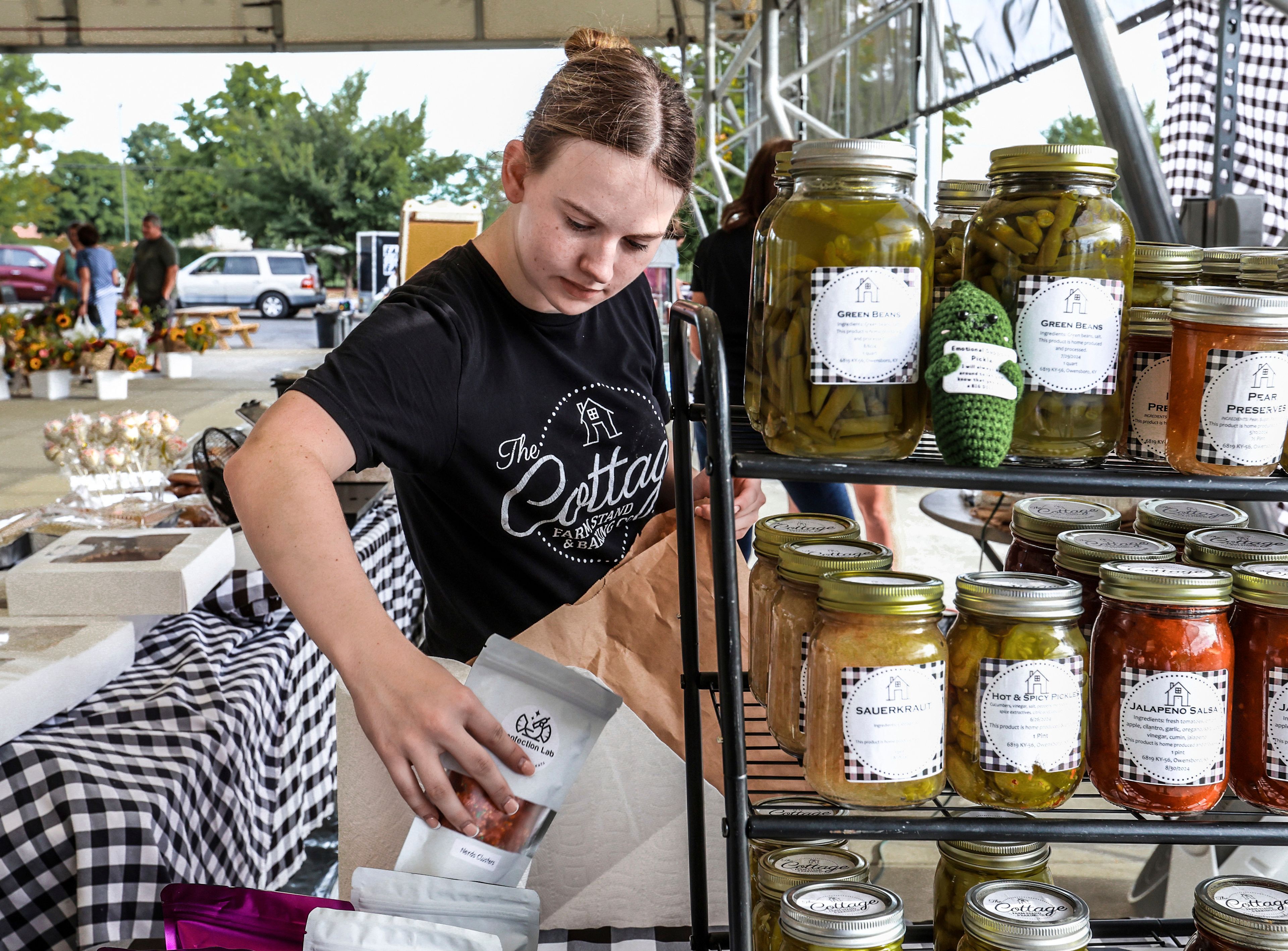 FILE - Lexia Smith stocks product while working in The Cottage Farm Stand & Baking Co. vendor booth set up at the Owensboro Regional Farmers' Market in Owensboro, Ky., on Aug. 31, 2024. (Greg Eans/The Messenger-Inquirer via AP)/The Messenger-Inquirer via AP, File)