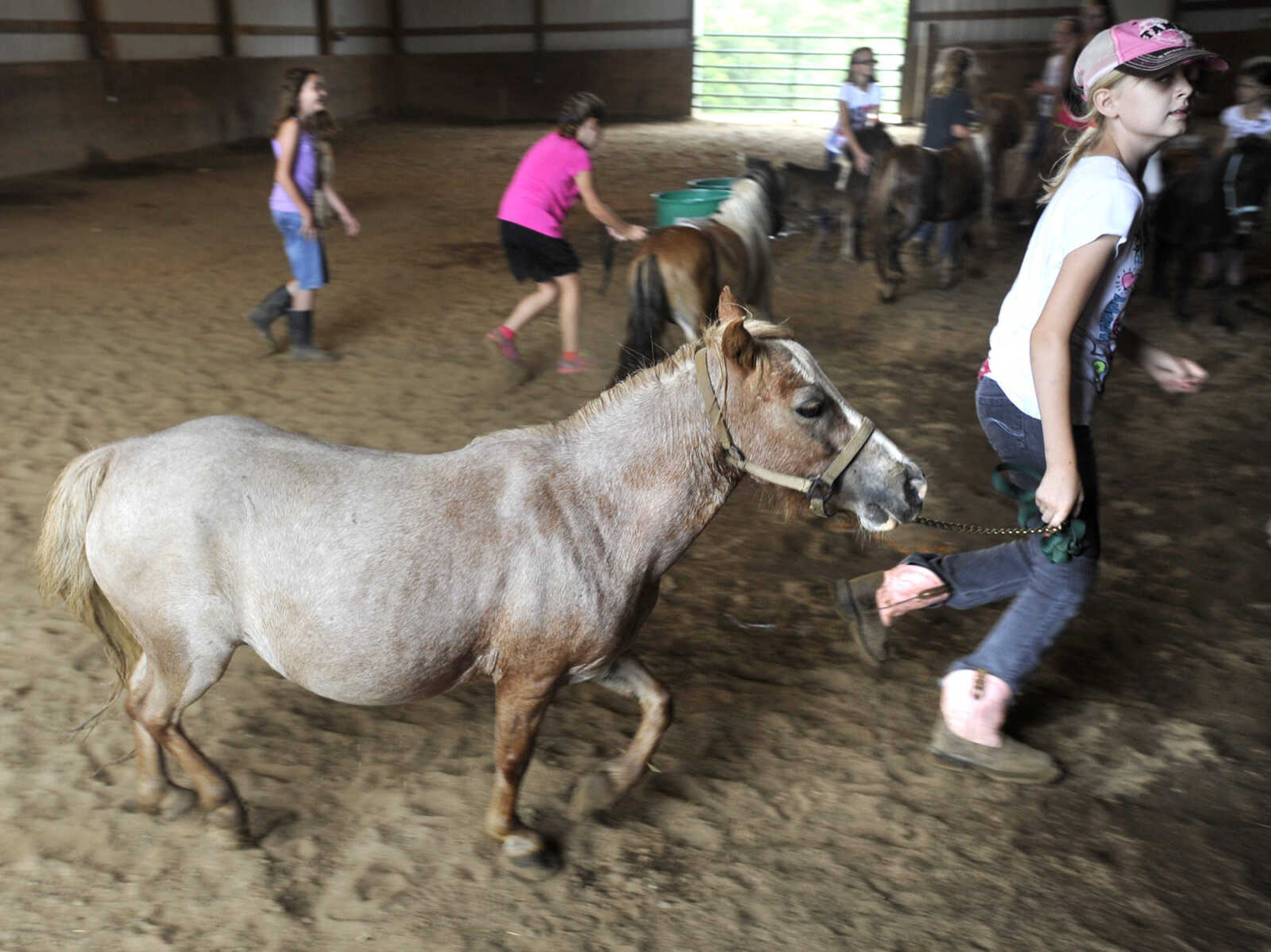 Emily Dockins leads Ruby in the barn at a horseback riding camp Monday, July 6, 2015 at Rolling Hills Farm west of Cape Girardeau.