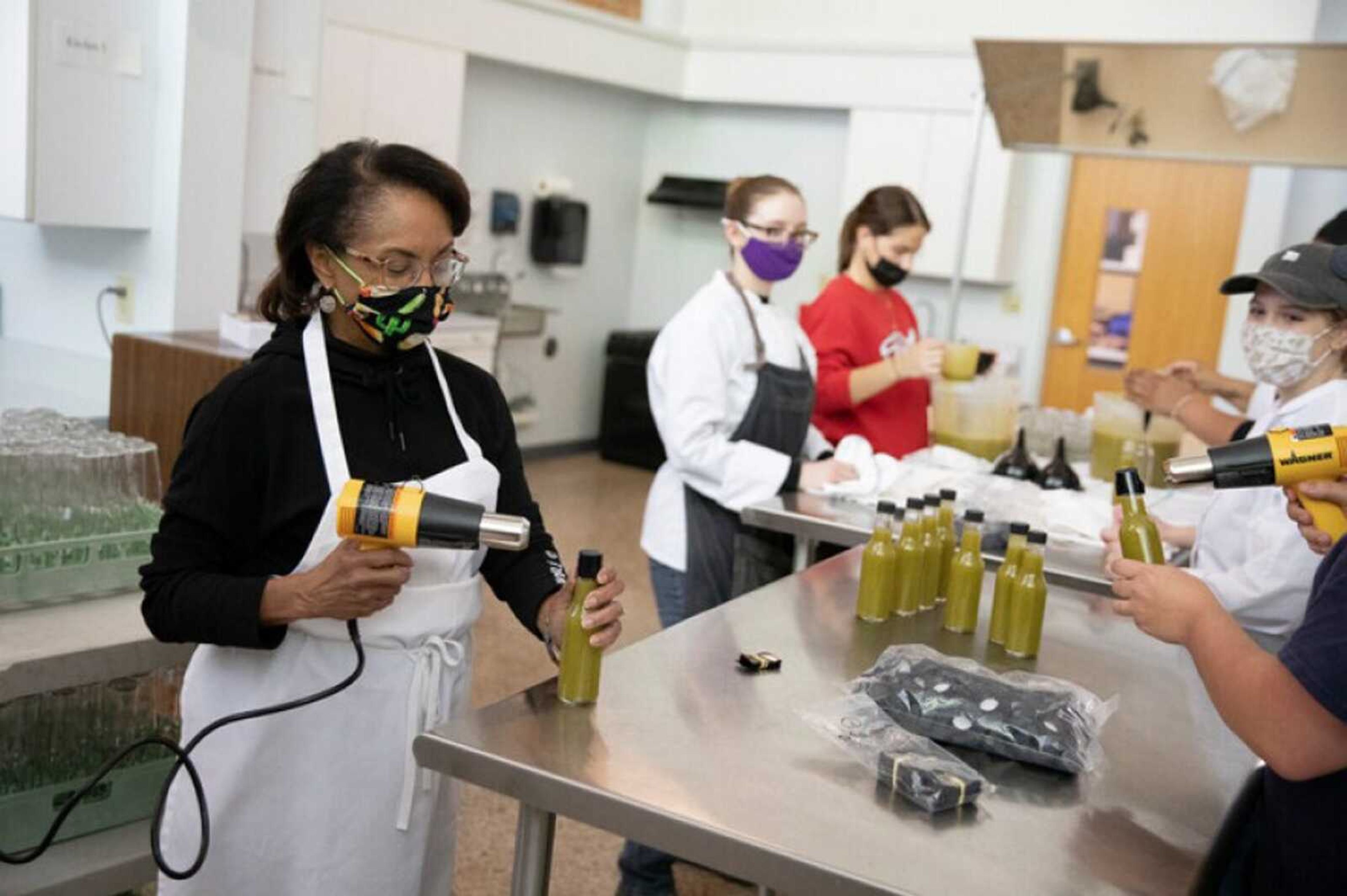 Quantella Noto, director of Southeast Missouri State University's hospitality management program, joins her students in producing locally-made green hot sauce sold at Catapult Creative House in Cape Girardeau last year. The labeling on the bottles, as with other food packaging, were in both customary (imperial) and metric measurements.