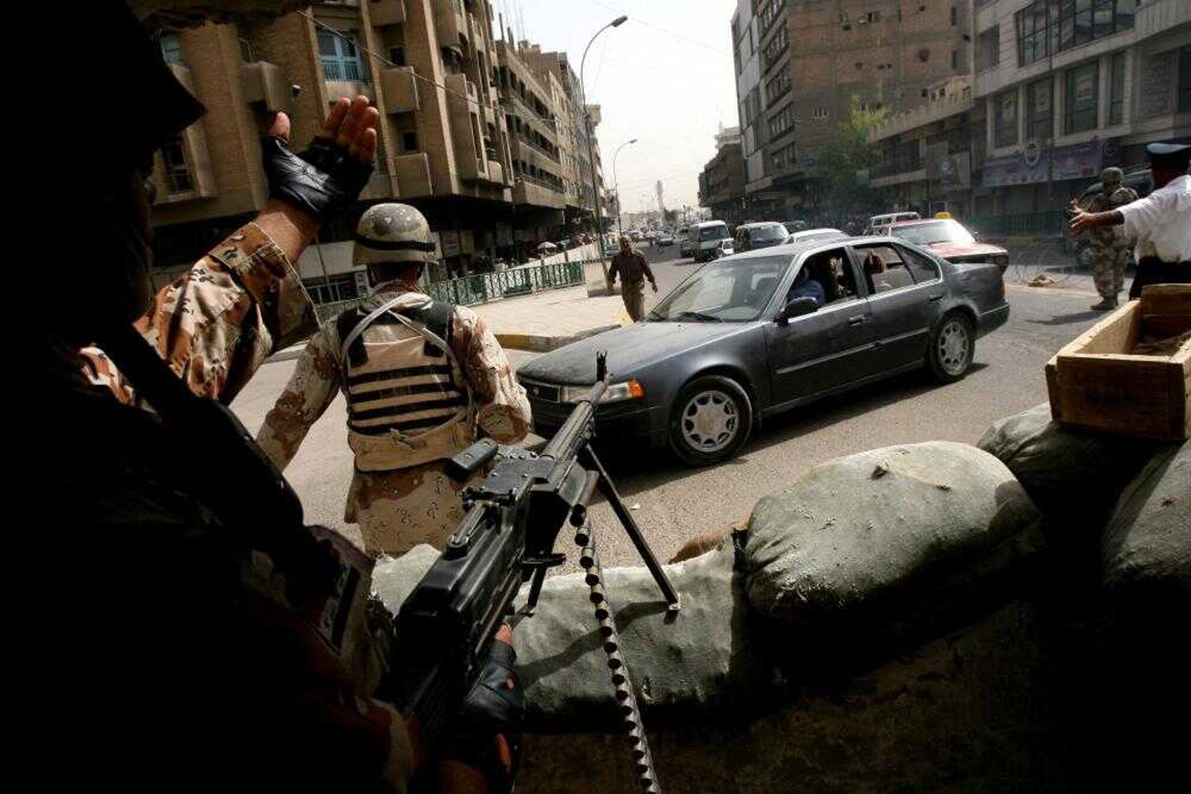 Iraqi soldiers and traffic police officers stopped a car Sunday at a check point in Baghdad. The U.S. military said Sunday that fourteen American soldiers were killed in three days in Iraq, including four in a single roadside bombing. (Khalid Mohammed ~ Associated Press)