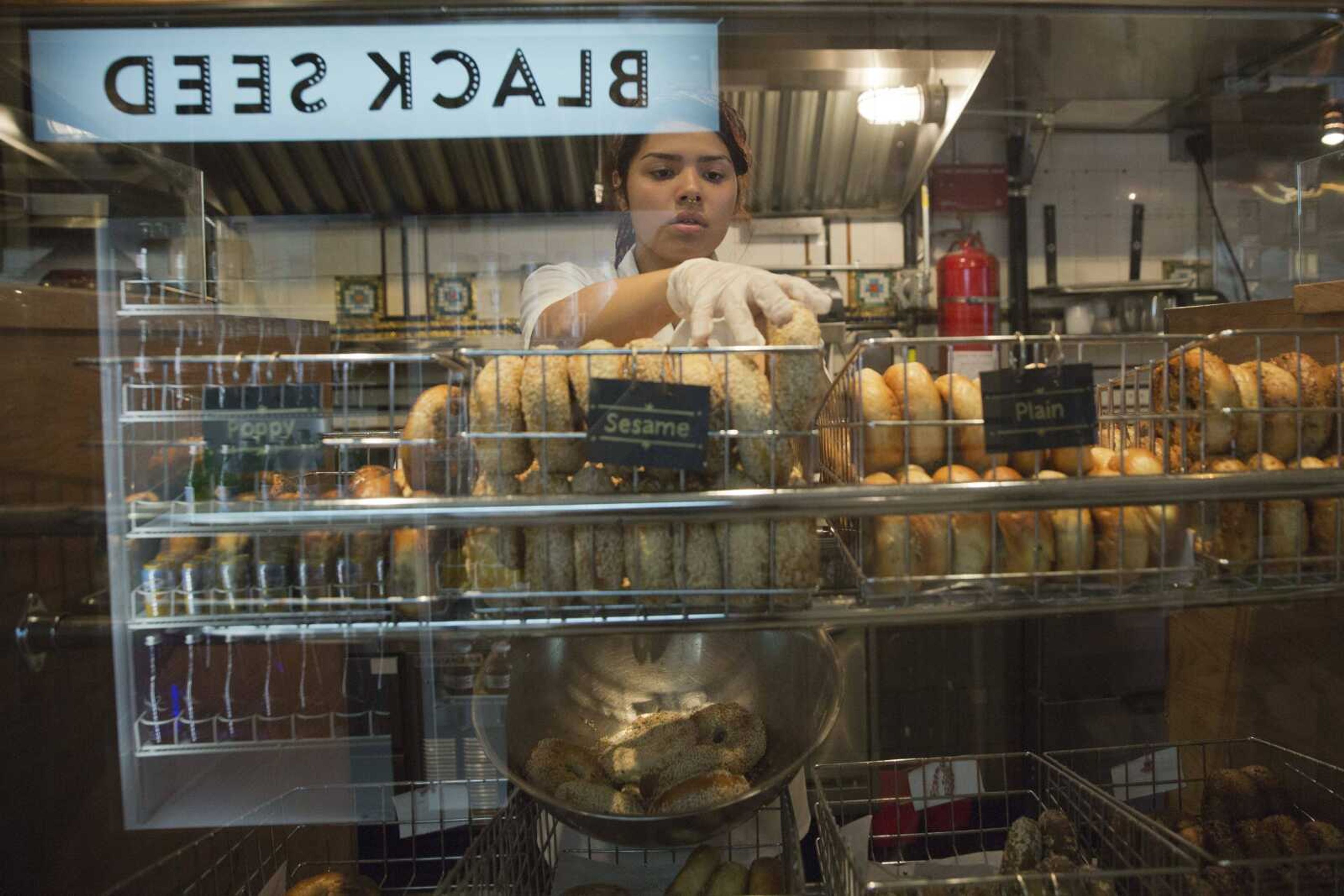 An employee of the Black Seed bagel shop arranges freshly baked bagels on the store's display May 27 in the East Village neighborhood of New York.