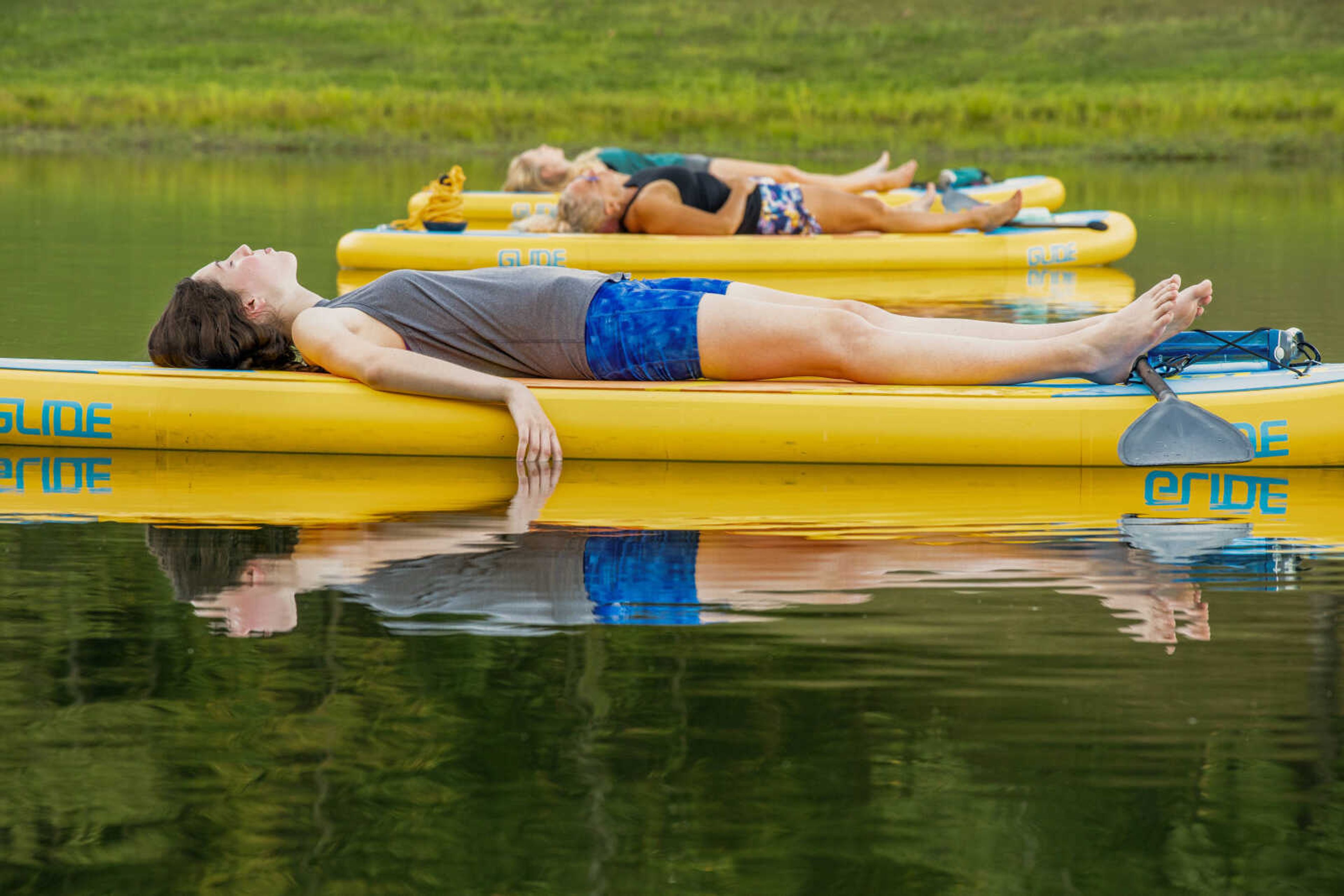 Jasmine Jones lays on a paddleboard in Lake Boutin at Trail of Tears State Park during guided relaxation. It was Jones' first time participating in a SUP yoga class.