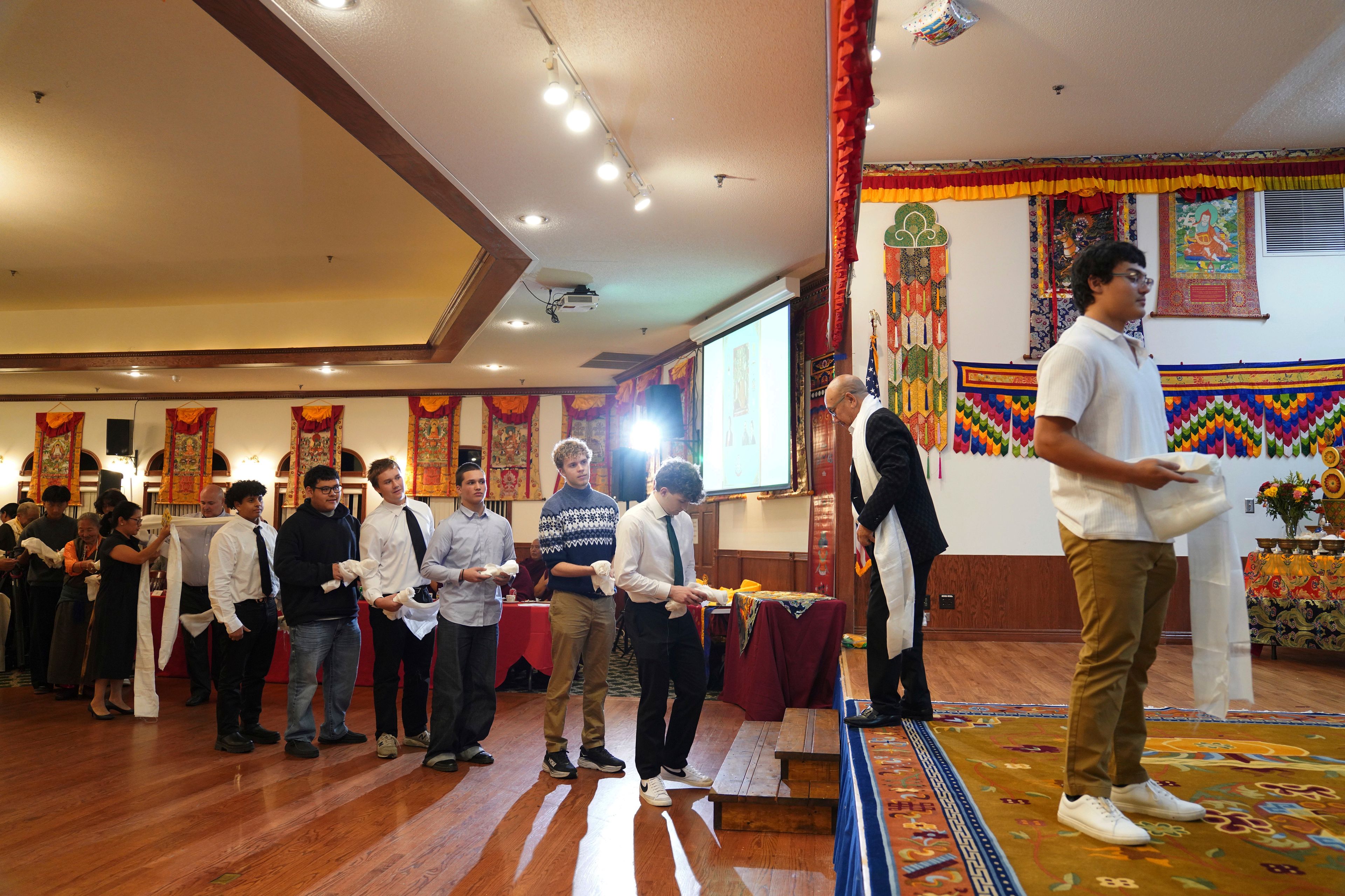 High school friends and fellow football players line up to present U.S.-born Buddhist lama, Jalue Dorje, with “khata,” the Tibetan ceremonial scarves that symbolize auspiciousness, at his 18th birthday and enthronement ceremony, in Isanti, Minn., on Saturday, Nov. 9, 2024. (AP Photo/Jessie Wardarski)