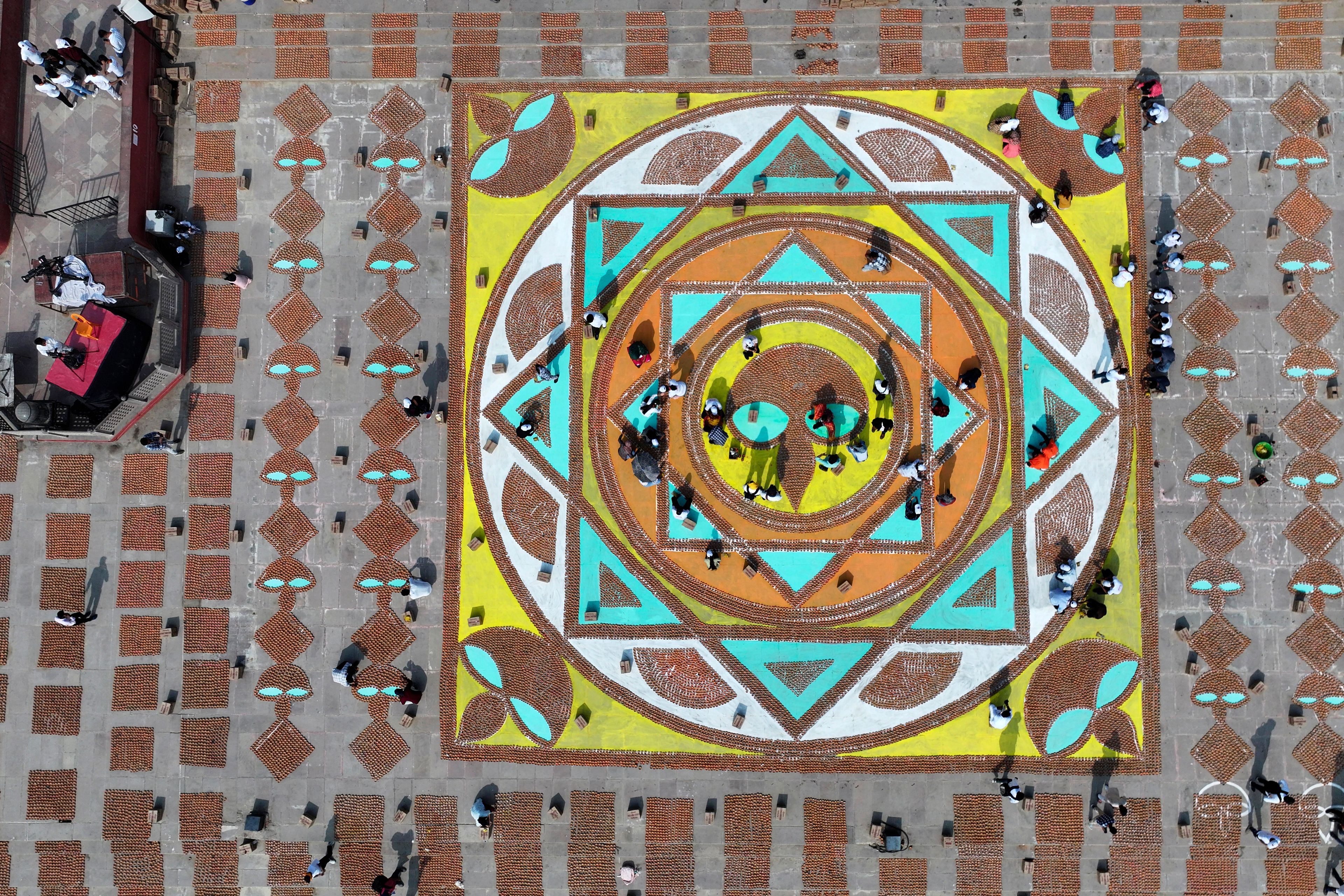 Volunteers give final touches to a geometric pattern using earthen oil lamps on the banks of the Saryu river during Deepotsav celebrations on the eve of Diwali, in Ayodhya, India, Wednesday, Oct. 30, 2024. (AP Photo/Rajesh Kumar Singh)