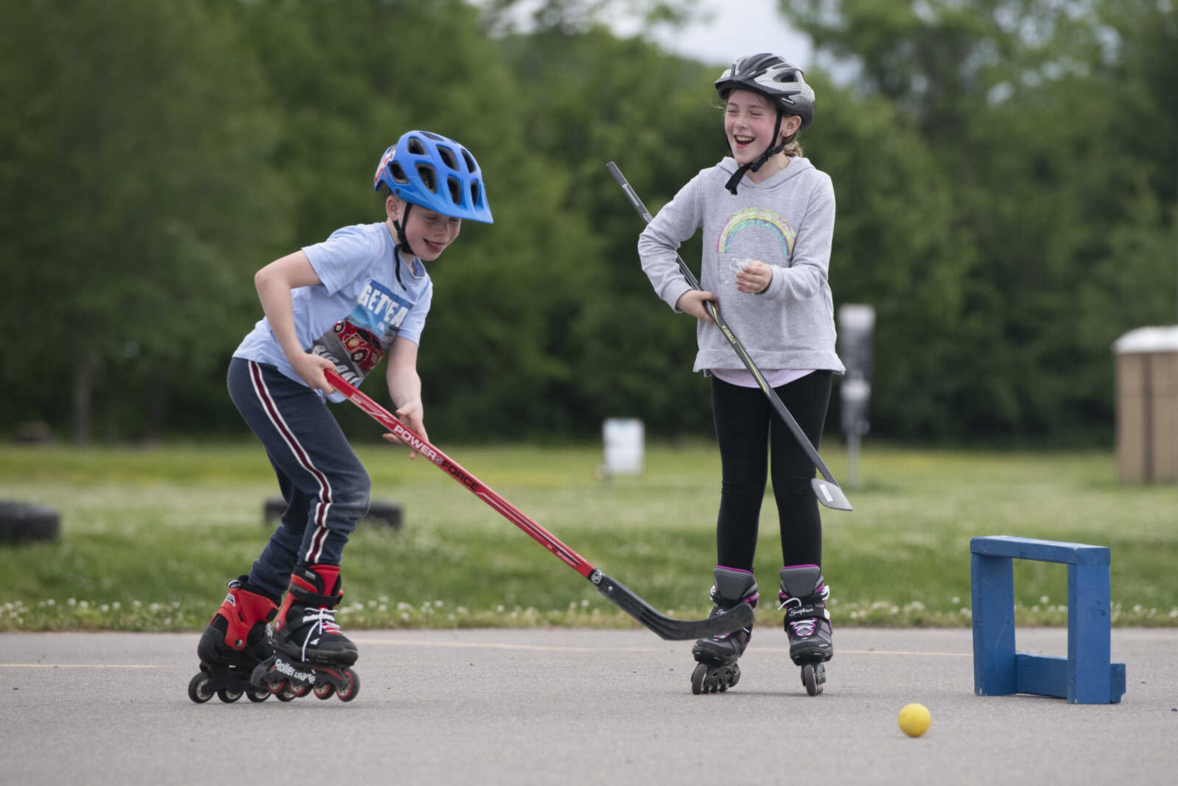 Henri Booch, 7, goes after a ball near his sister Emma Booch, 9, while playing hockey Wednesday, May 20, 2020, at a parking lot near Cape Splash Family Aquatic Center in Cape Girardeau.