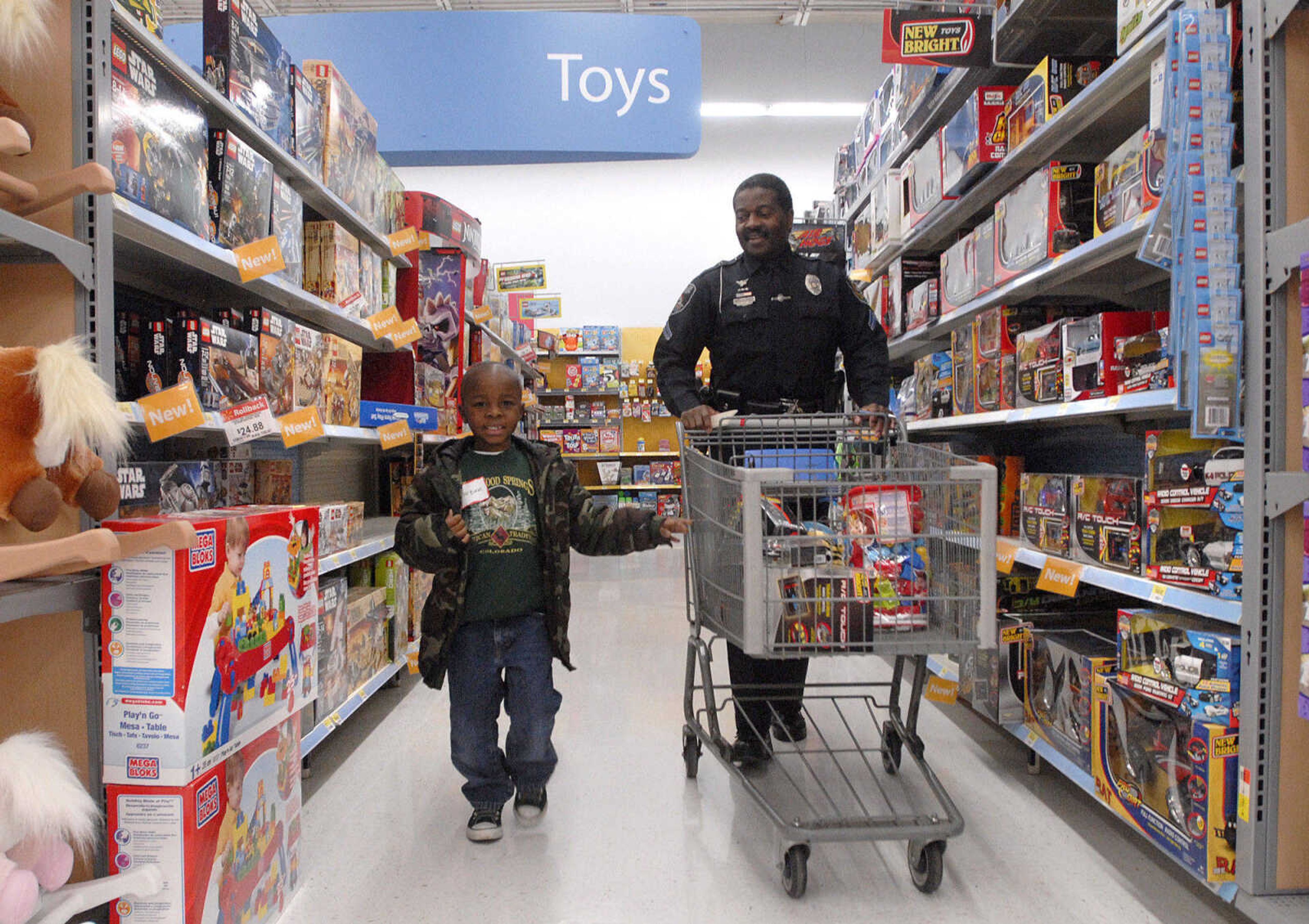 LAURA SIMON ~ lsimon@semissourian.com
Marquan Long walks alonside Officer Ike Hammonds with the Cape Girardeau Police Department Tuesday morning, Dec. 6, 2011as they shop for toys at Walmart in Cape Girardeau. Long was one of around 100 children that got to Shop with a Hero Tuesday morning. This is the 20th year that Walmart has held the Christmas shopping event that allows children to shop with donated money for toys, clothing or any item of their choice within the amount raised. This year each child received around $85 to spend with the help of local police officers, firefighters and first responders.