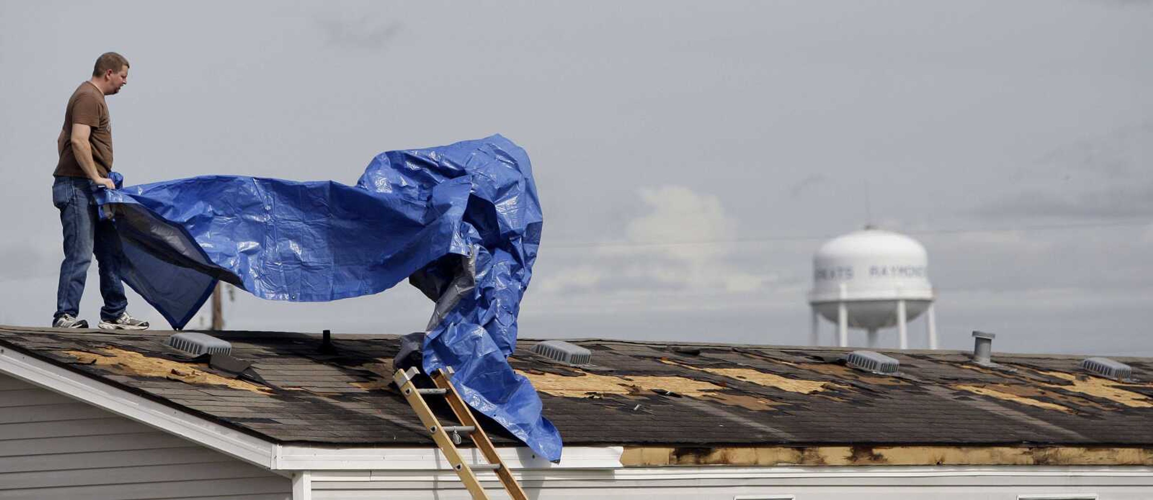 David Anderson covers his damaged roof with a blue tarp, Tuesday, Sept. 7, 2010 in Raymondville, Texas, after tropical storm Hermine swept through the area. (AP Photo/Eric Gay)