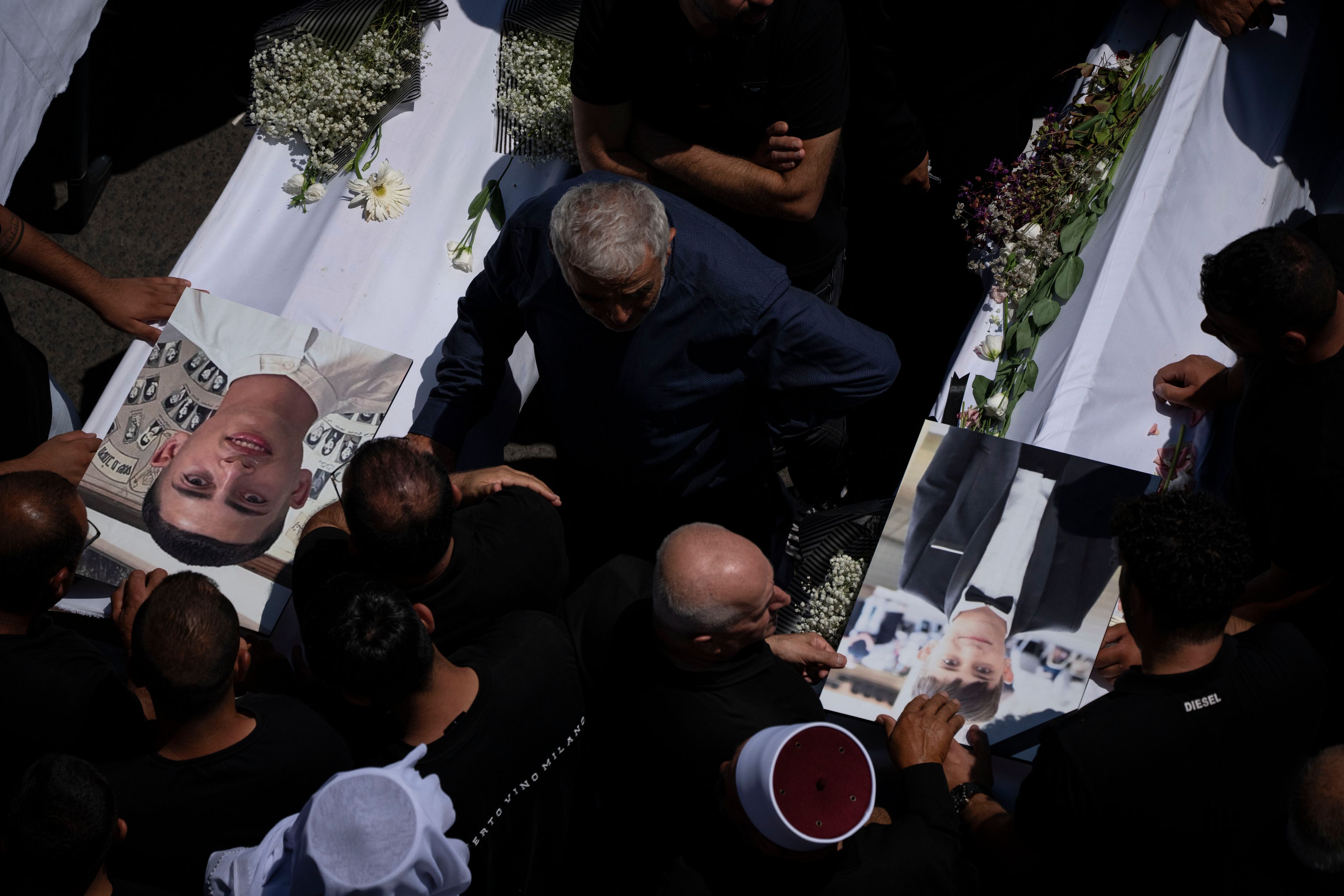 Mourners from the Druze minority surround the bodies of some of the 12 children and teens killed in a rocket strike at a soccer field, during their funeral, in the village of Majdal Shams, in the Israeli-annexed Golan Heights, Sunday, July 28, 2024. It's the deadliest strike on an Israeli target along the country's northern border since the fighting between Israel and the Lebanese militant group Hezbollah began. (AP Photo/Leo Correa)