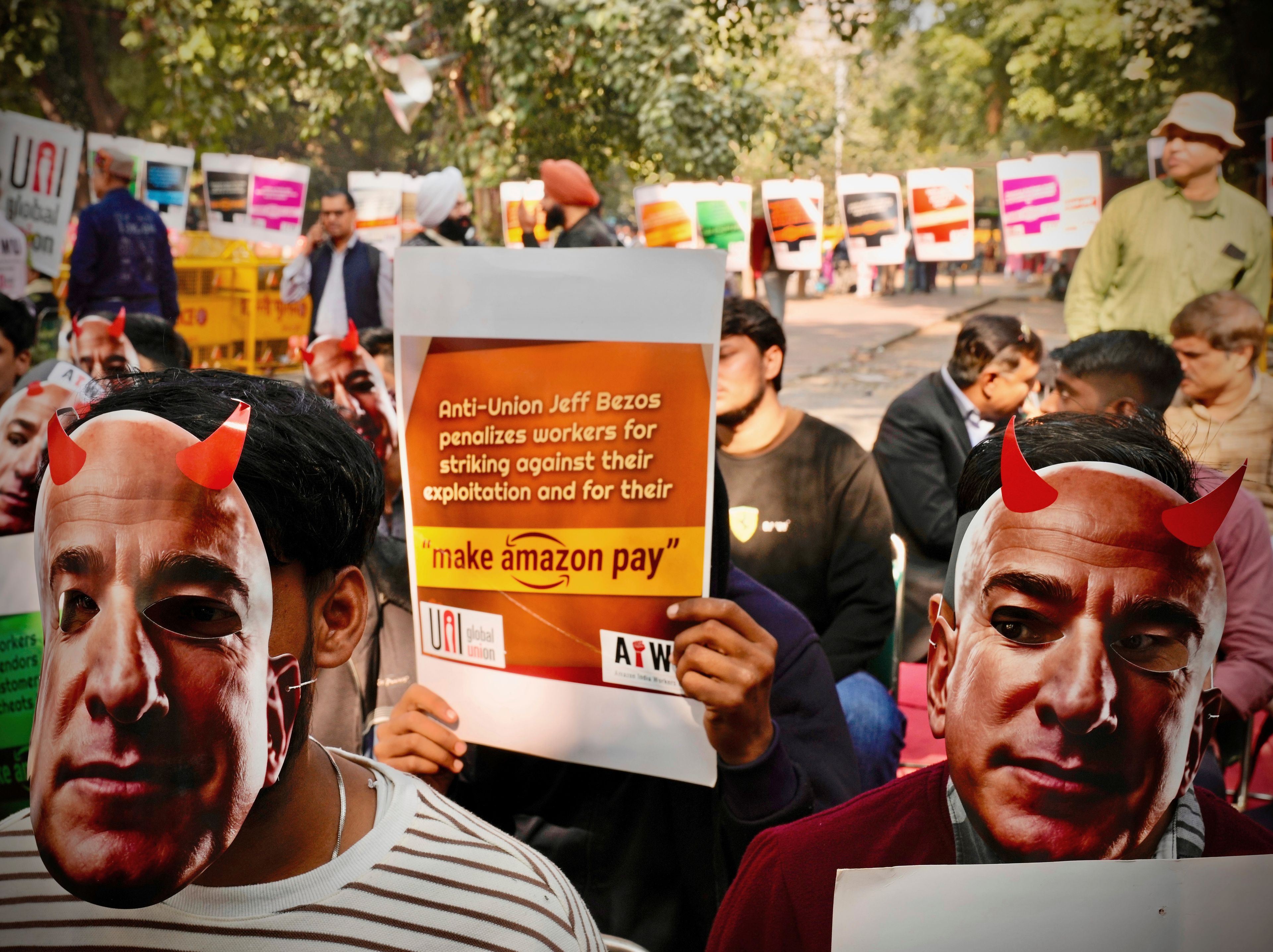 Participants wear paper masks in the likeness of Amazon's Jeff Bezos during a protest by warehouse workers and delivery drivers against the Seattle-based company, demanding higher wages and better working conditions, in New Delhi, India, Friday, Nov. 29, 2024. (AP Photo/Manish Swarup)