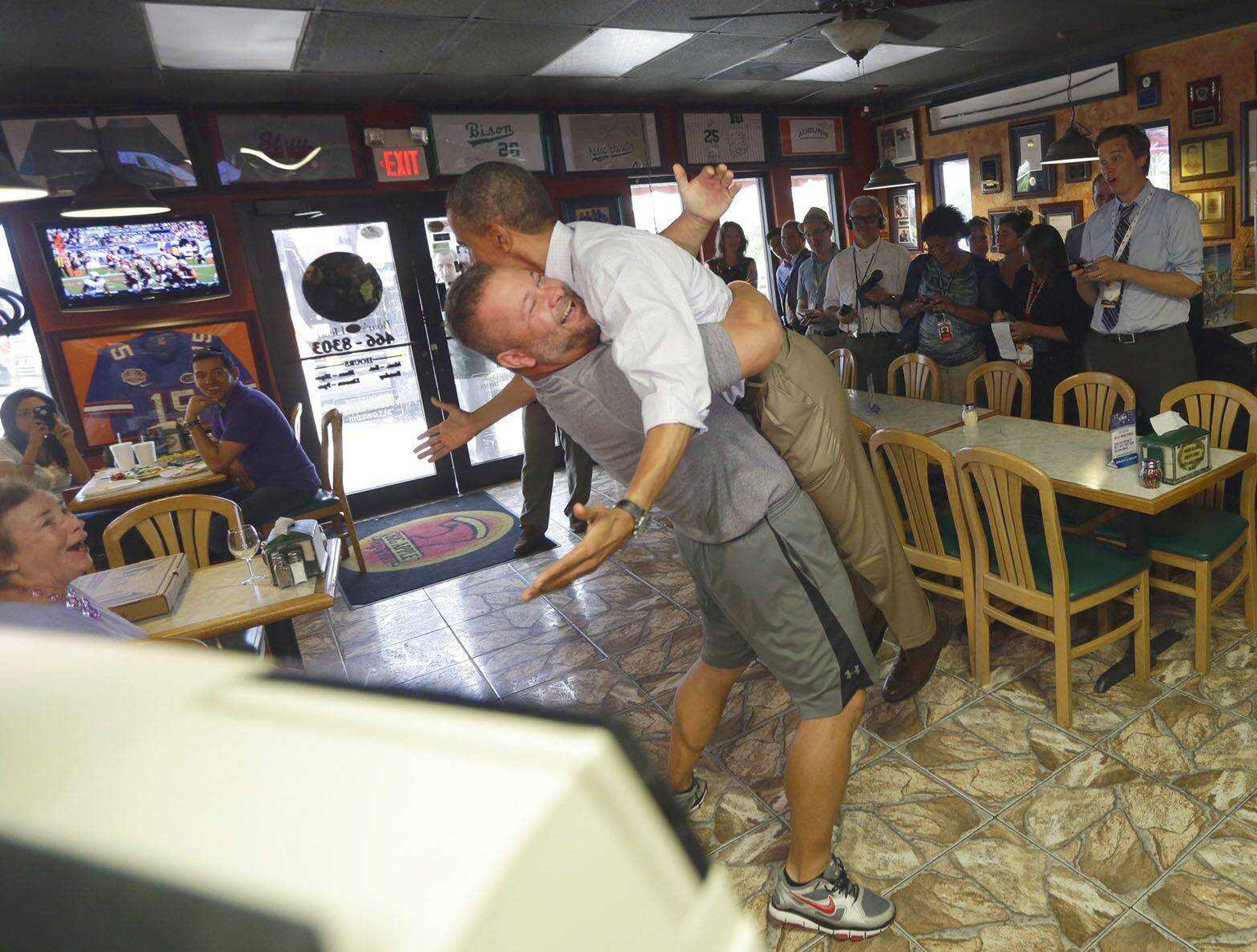 President Barack Obama, right, is picked up and lifted off the ground by Scott Van Duzer, owner of Big Apple Pizza and Pasta Italian Restaurant during an unannounced stop Sunday in Fort Pierce, Fla. (Pablo Martinez Monsivais ~ Associated Press)