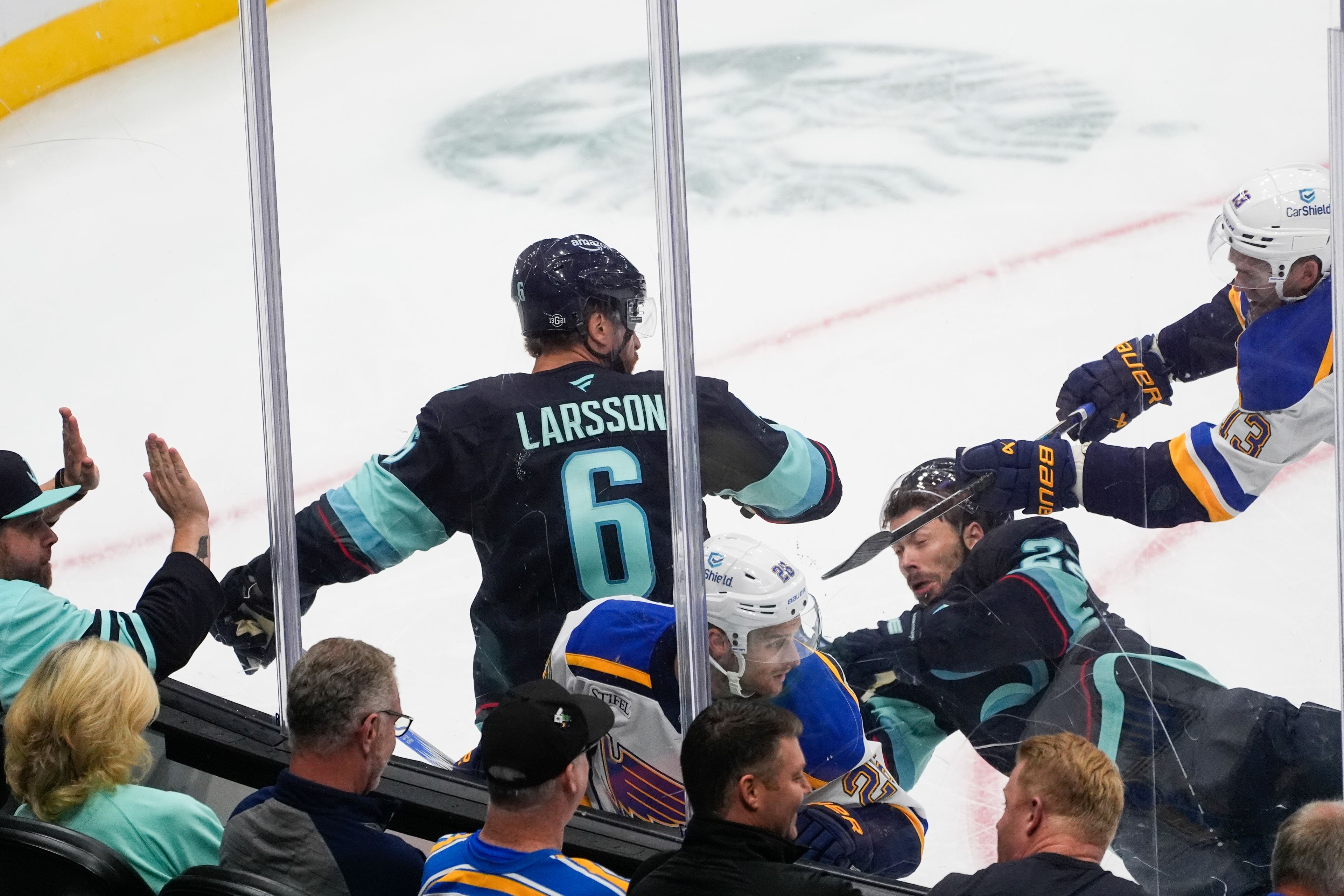 Seattle Kraken defenseman Adam Larsson (6) looks back as right wing Oliver Bjorkstrand (22) falls in a collision with St. Louis Blues left wing Nathan Walker (26) and right wing Alexey Toropchenko (13) during the first period of an NHL hockey game Tuesday, Oct. 8, 2024, in Seattle. (AP Photo/Lindsey Wasson)