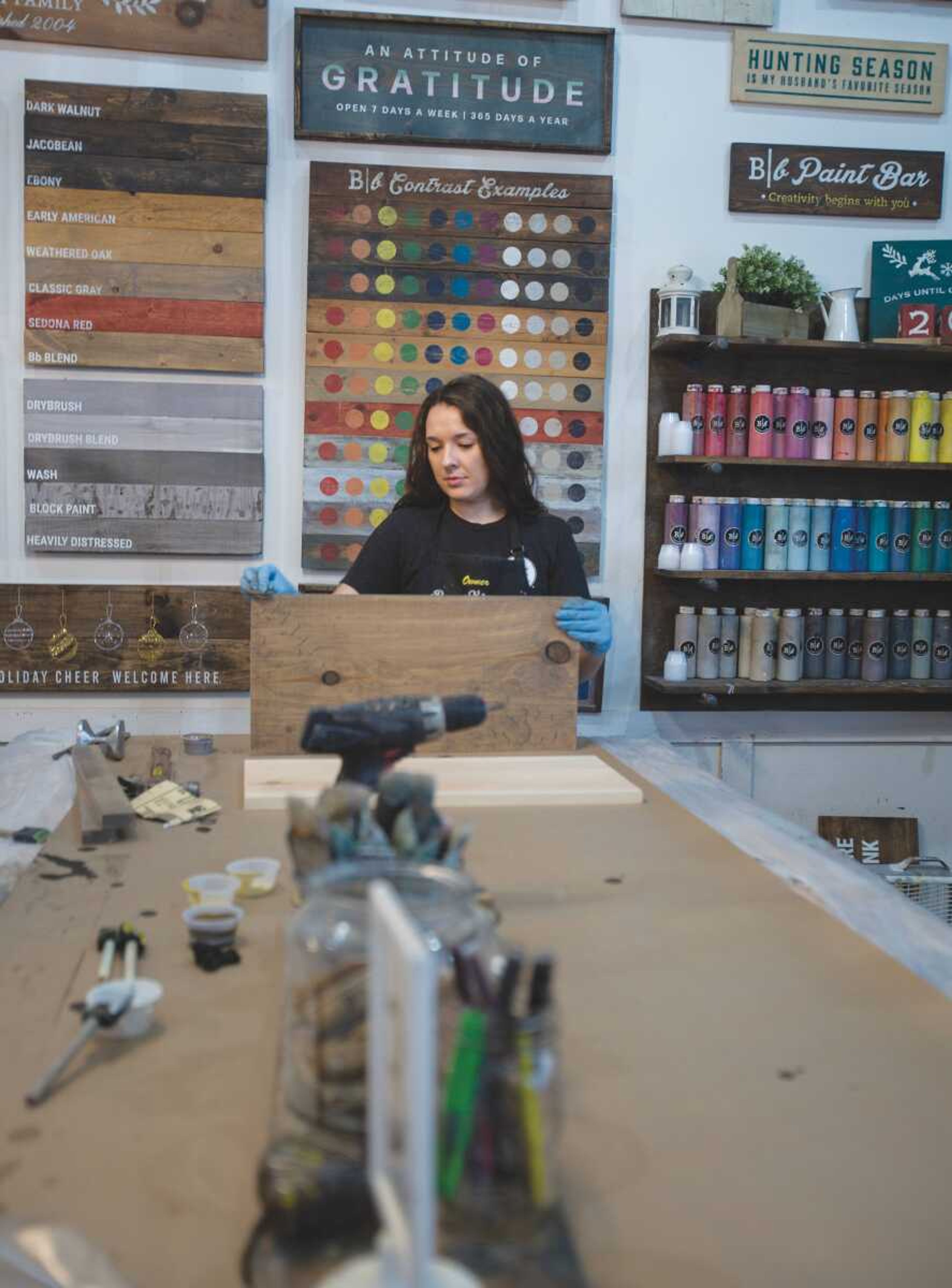  Brittney Swicionis sands a wooden board at Board & Brush Creative Studio in Cape Girardeau. Swiconis owns the business and helps instruct customers during the wood sign making process. 