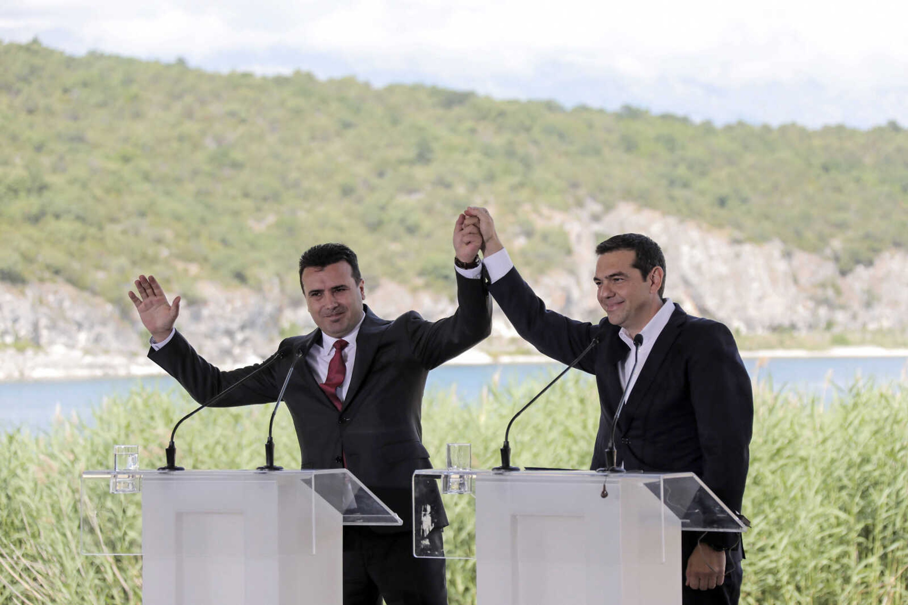 Greek Prime Minister Alexis Tsipras, right, and his Macedonian counterpart Zoran Zaev, raise their hands Sunday during a signing agreement for Macedonia's new name in the village of Psarades, Prespes Greece. The preliminary deal launches a long process that will last several months. If successful, it will end a decades-long dispute between neighbors Greece and Macedonia -- which will be renamed North Macedonia.