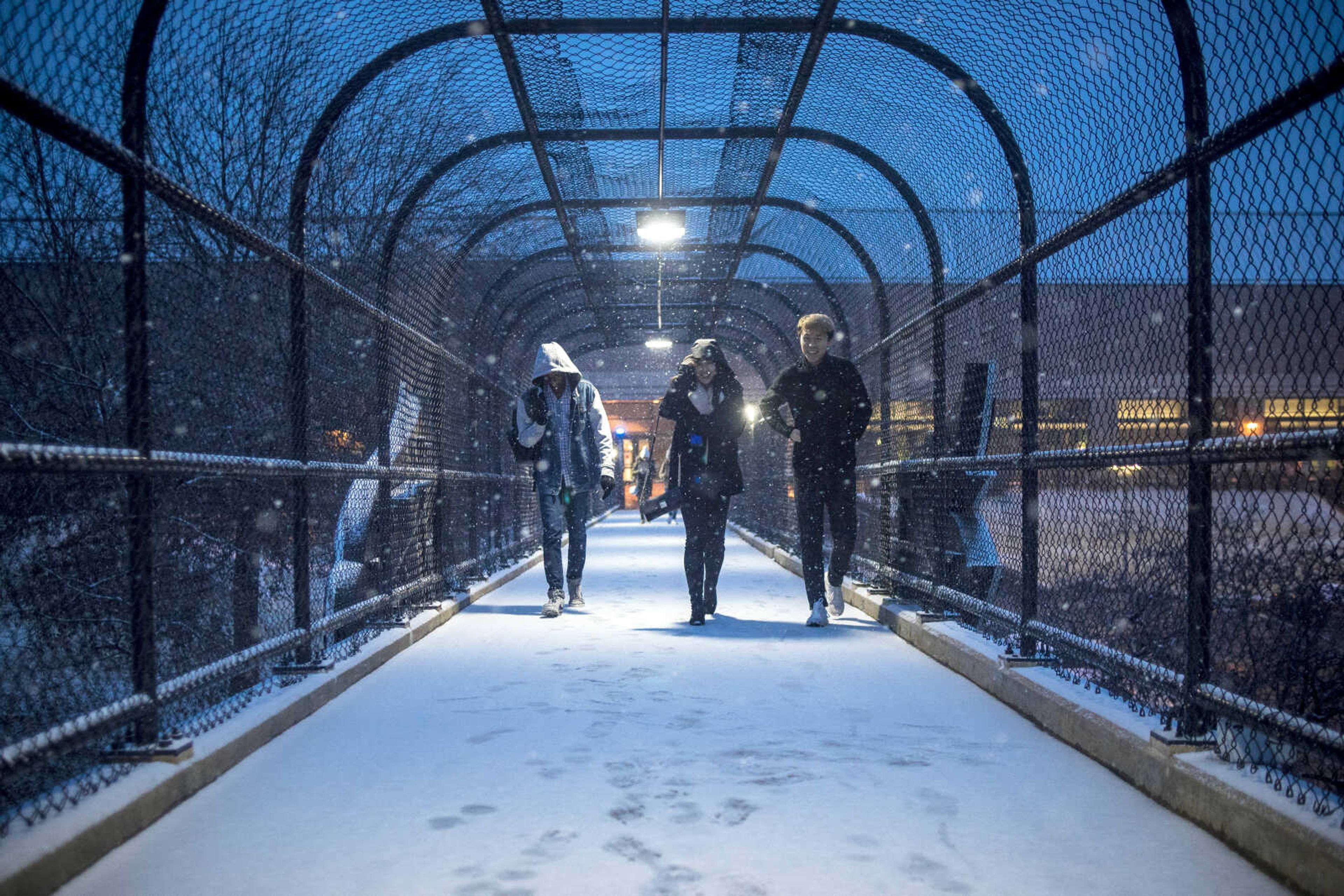 Jeffrey Oyelaja, Christine Dong and Hanming Fan cross a bridge to get to the Southeast Missouri State University Campus for dinner as snow begins to fall Friday, Jan. 11, 2019.