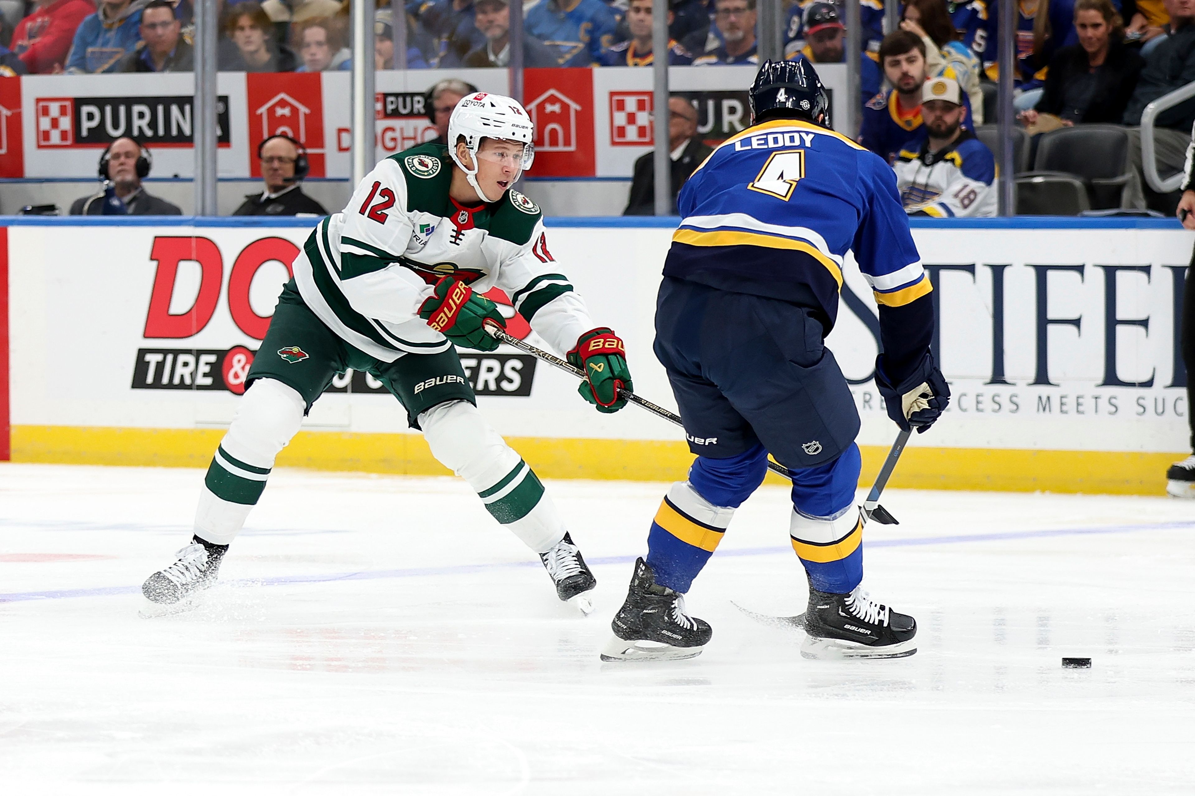 Minnesota Wild's Matt Boldy (12) passes the puck while St. Louis Blues' Nick Leddy (4) defends during the first period of an NHL hockey game Tuesday, Oct. 15, 2024, in St. Louis. (AP Photo/Scott Kane)