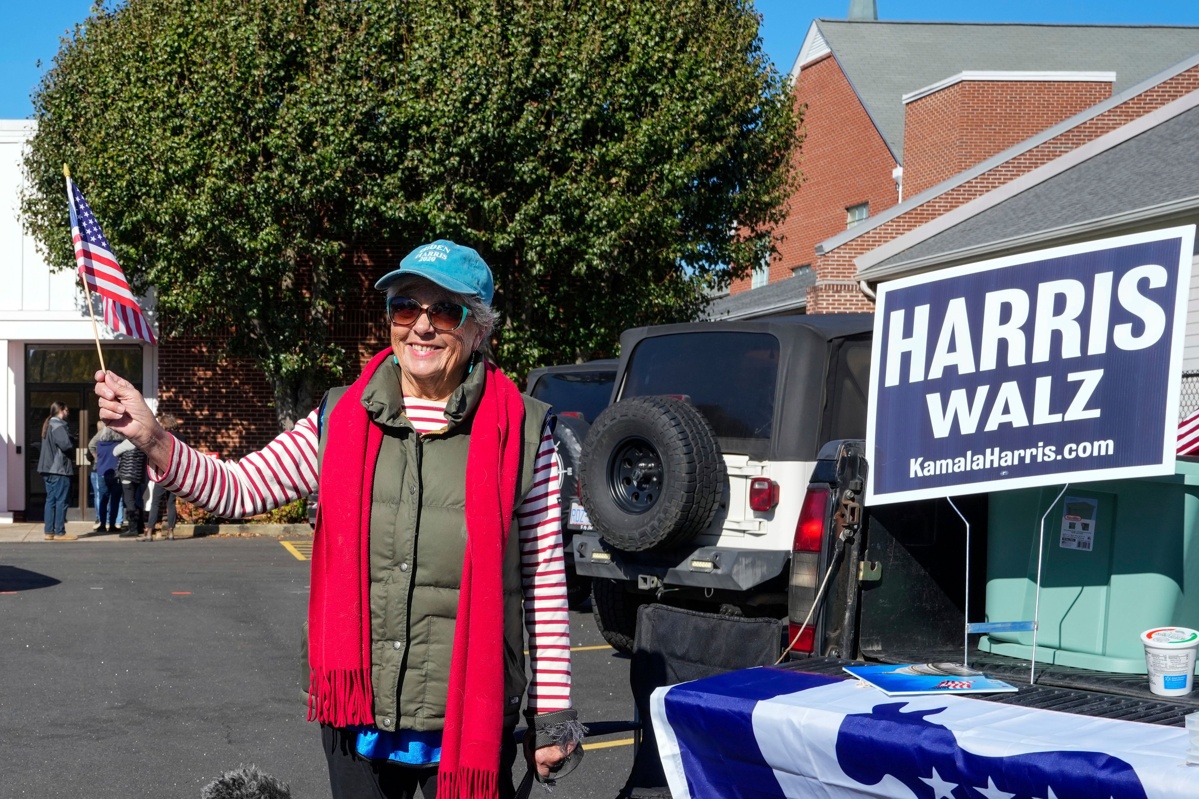 Outside the Rutherford County Annex Building where early voting is taking place, Susan McGowan waves a United States flag in support of Vice President Kamala Harris and Governor Tim Walz, Thursday, October 17, 2024 in Rutherfordton, N.C. (AP Photo/Kathy Kmonicek)