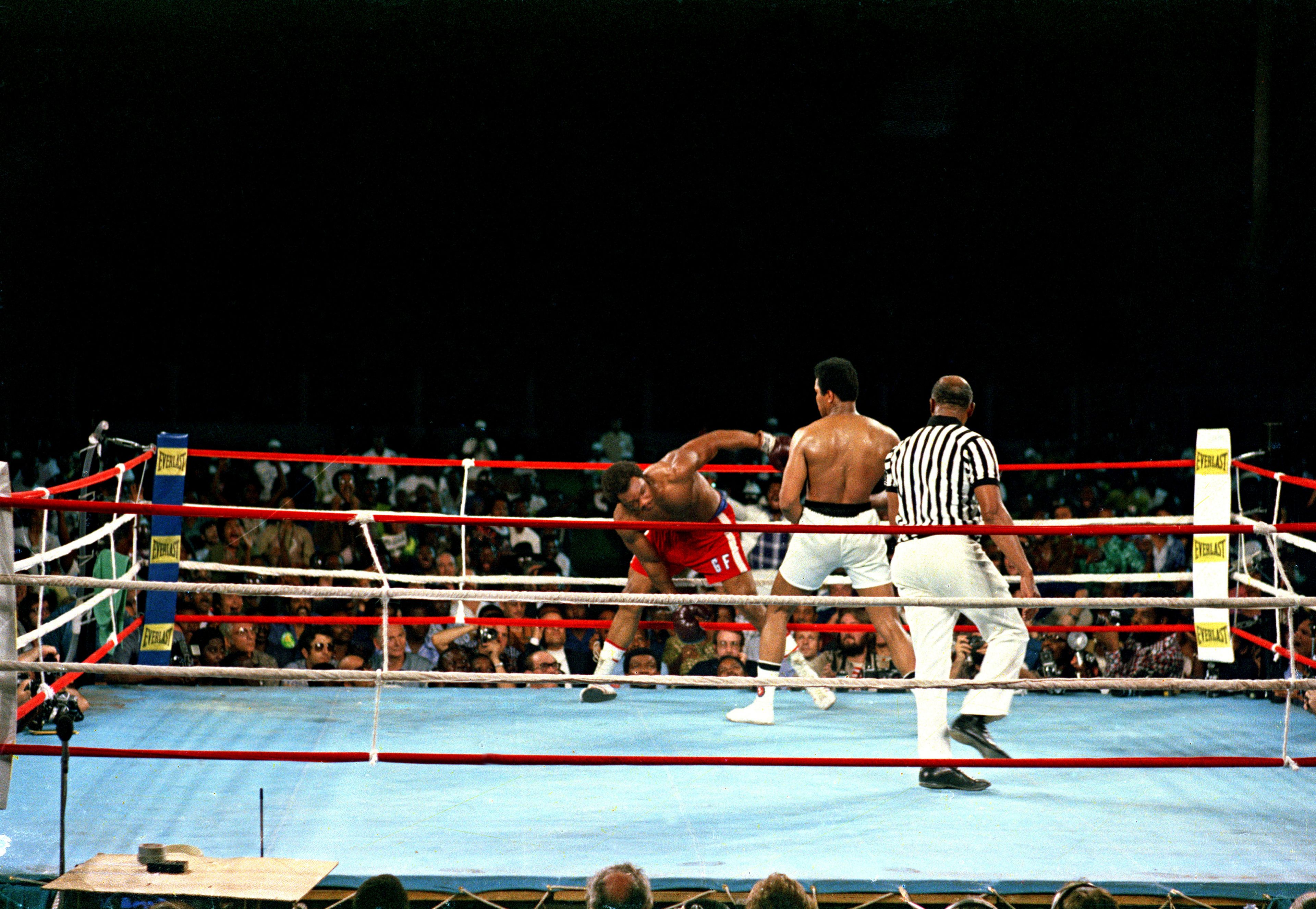 FILE - Challenger Muhammad Ali watches as defending world champion George Foreman struggles to keep his balance during the WBA/WBC championship bout in Kinshasa, Zaire, on Oct. 30, 1974. (AP Photo, File)