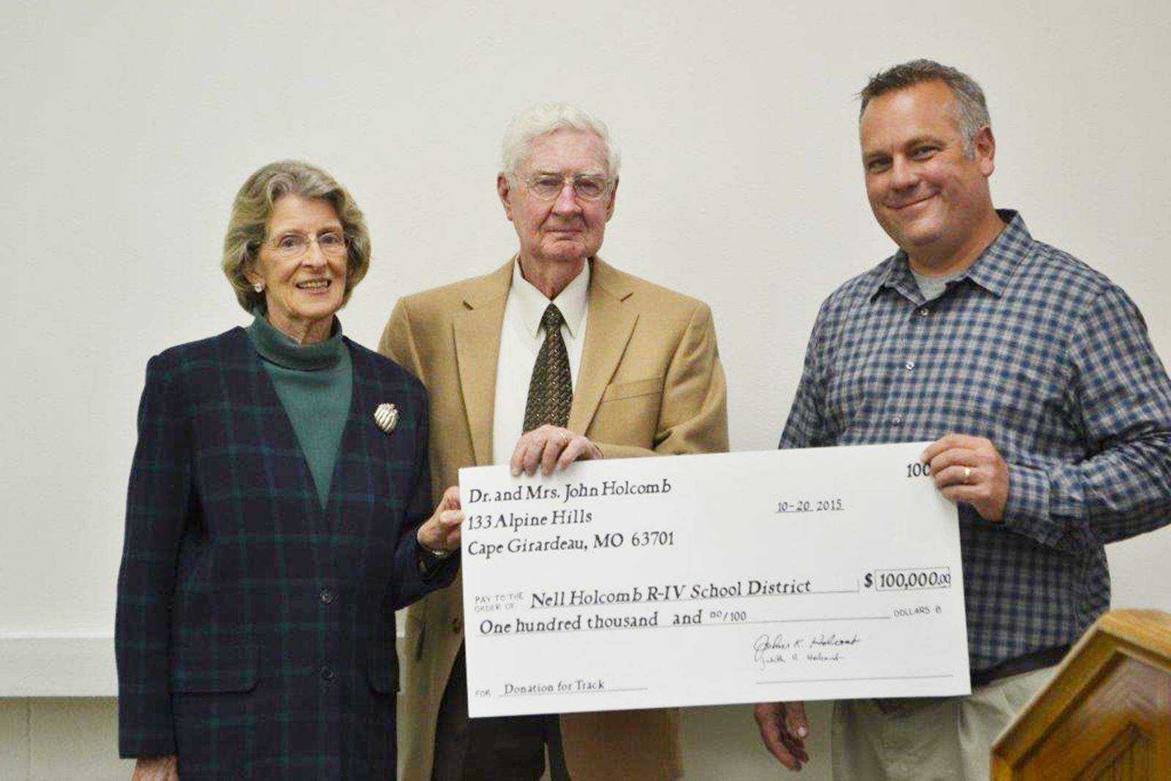 Judy Holcomb, left, and Dr. John Holcomb present a check to Blake Tiemann, Nell Holcomb School Board president. (Submitted photo)