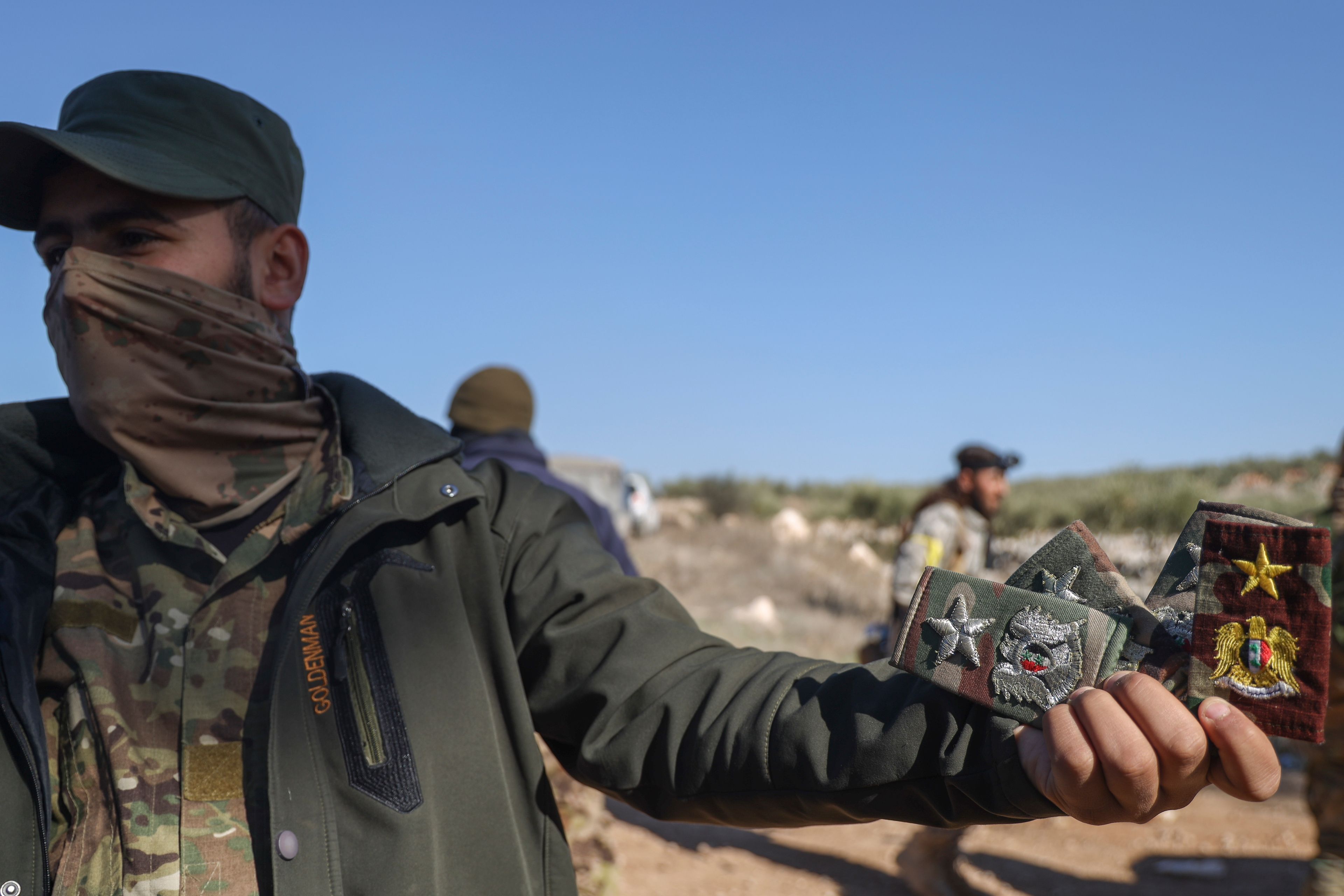 A Syrian opposition fighter displays badges allegedly belonging to Syrian army officers uniforms in Anjara, western outskirts of Aleppo, Syria, Thursday Nov. 28, 2024. (AP Photo/Omar Albam)