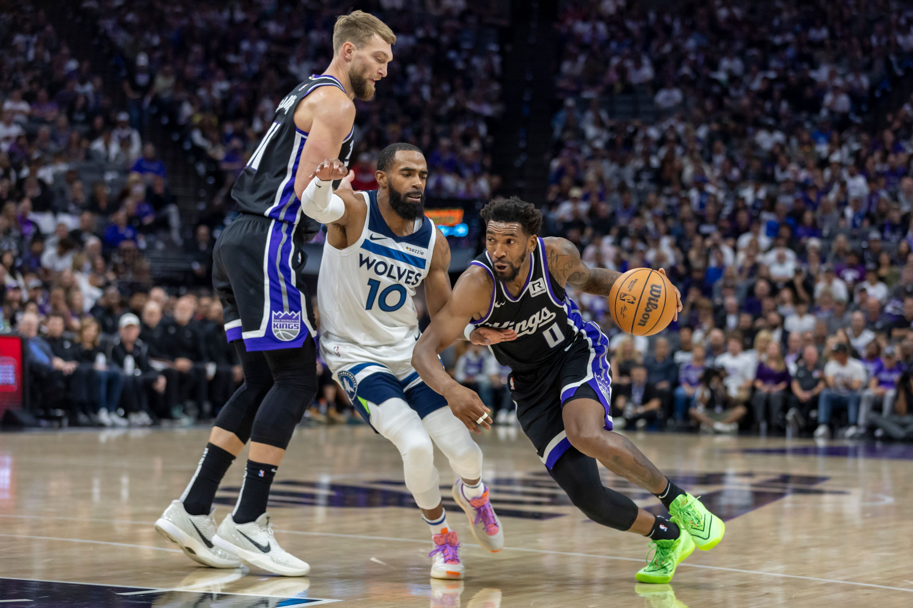 Sacramento Kings guard Malik Monk (0) dribbles past Minnesota Timberwolves guard Mike Conley (10) as Kings forward Domantas Sabonis (11) sets a pick during the first half of an NBA basketball game Thursday, Oct. 24, 2024, in Sacramento, Calif. (AP Photo/Sara Nevis)