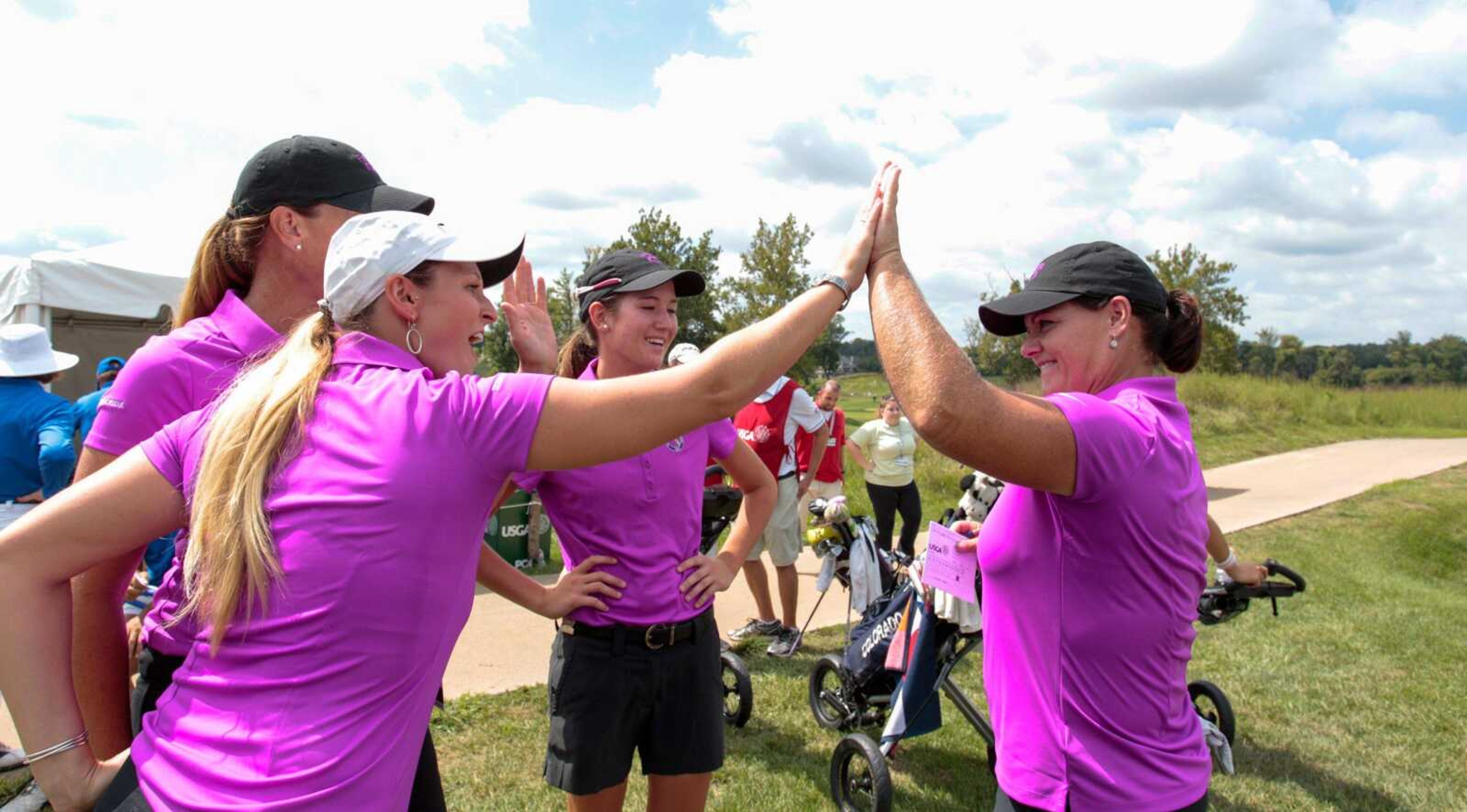 Jenna  Masnyk, left-white cap, the non playing caption of team Florida high fives Tara Joy-Connelly, at right, as she walked off the 18th green after finishing the morning round 5 under, 67 during the first morning at the 2015 Women's State Team at Dalhousie Golf Club in Cape Girardeau, Mo. on Thursday, Sept. 10, 2015.  Team members Meghan Stasi and Kendall Griffin look on. (Copyright USGA/Steven Gibbons)