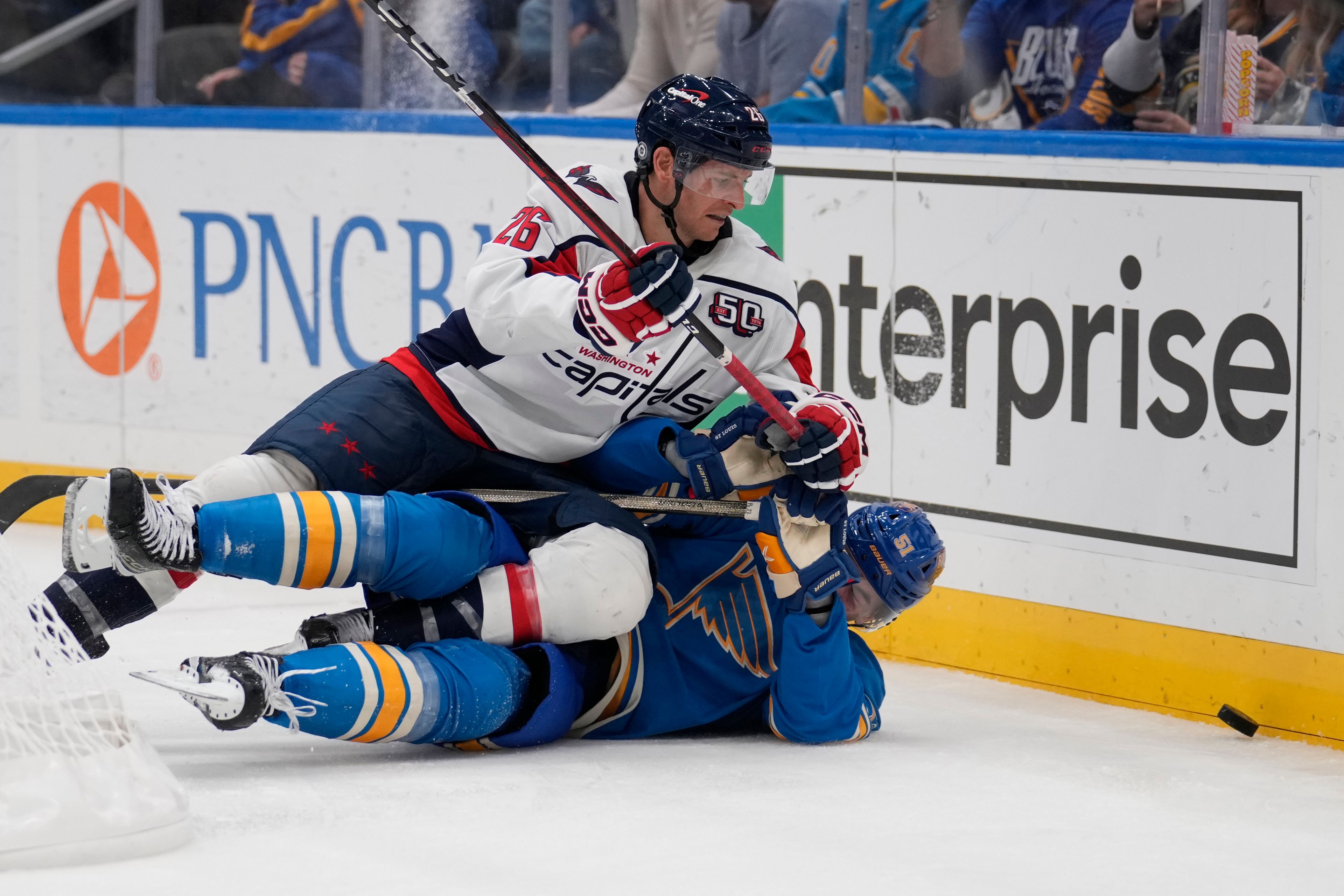 Washington Capitals' Nic Dowd (26) and St. Louis Blues' Matthew Kessel battle for a loose puck along the boards during the third period of an NHL hockey game Saturday, Nov. 9, 2024, in St. Louis. (AP Photo/Jeff Roberson)