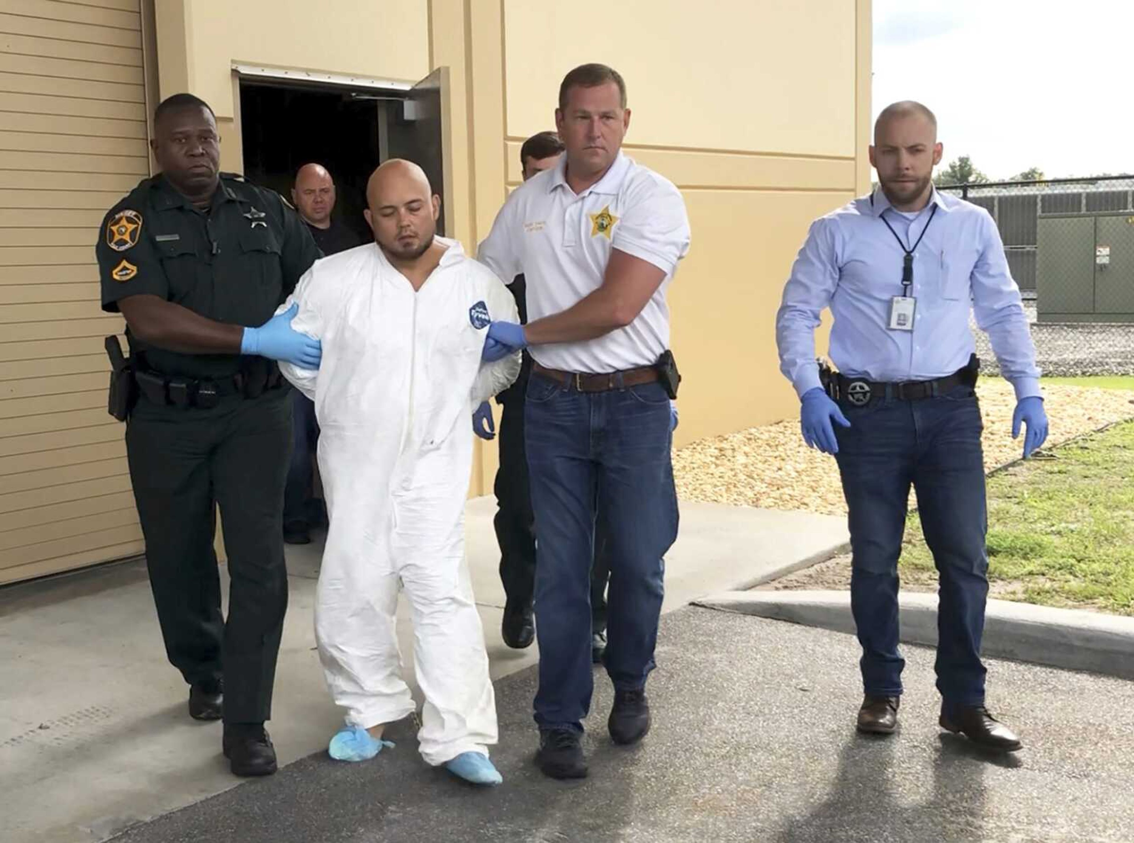 Quadruple murder suspect Bryan Riley is led from the Polk County Sheriff's Office on Sunday in Lakeland, Florida, by deputy Steve Neil, left, Capt. Bart Davis and detective Brett Bulman.