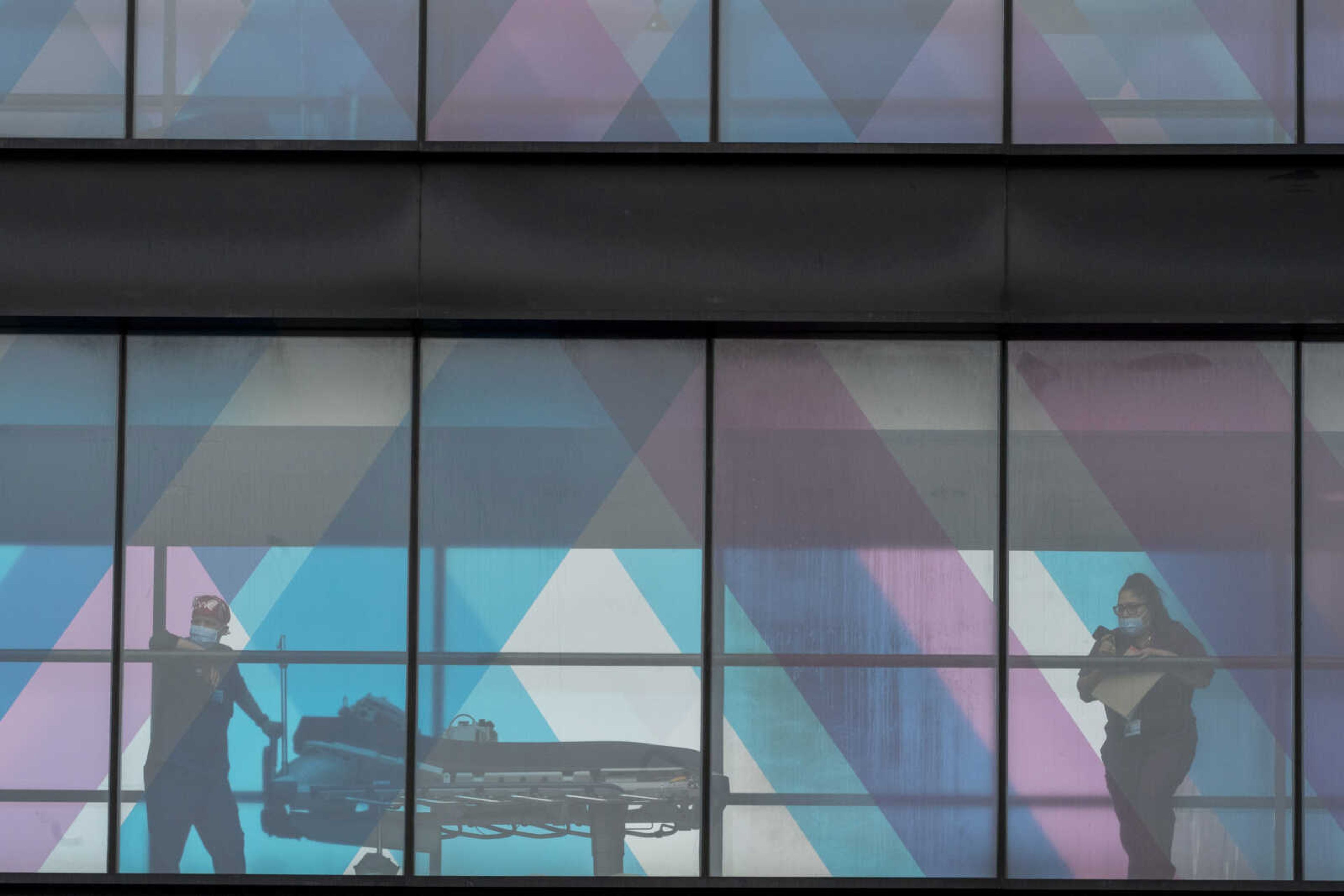 Health care workers look out the window at NY Presbyterian and Mount Sinai from an overpass at Mount Sinai Hospital on March 16, 2021, in New York. In a poll from AP-NORC Center for Public Affairs Research, about half of Americans say they currently have credit card debt, 4 in 10 are dealing with auto loans, and about one in four have medical debt.