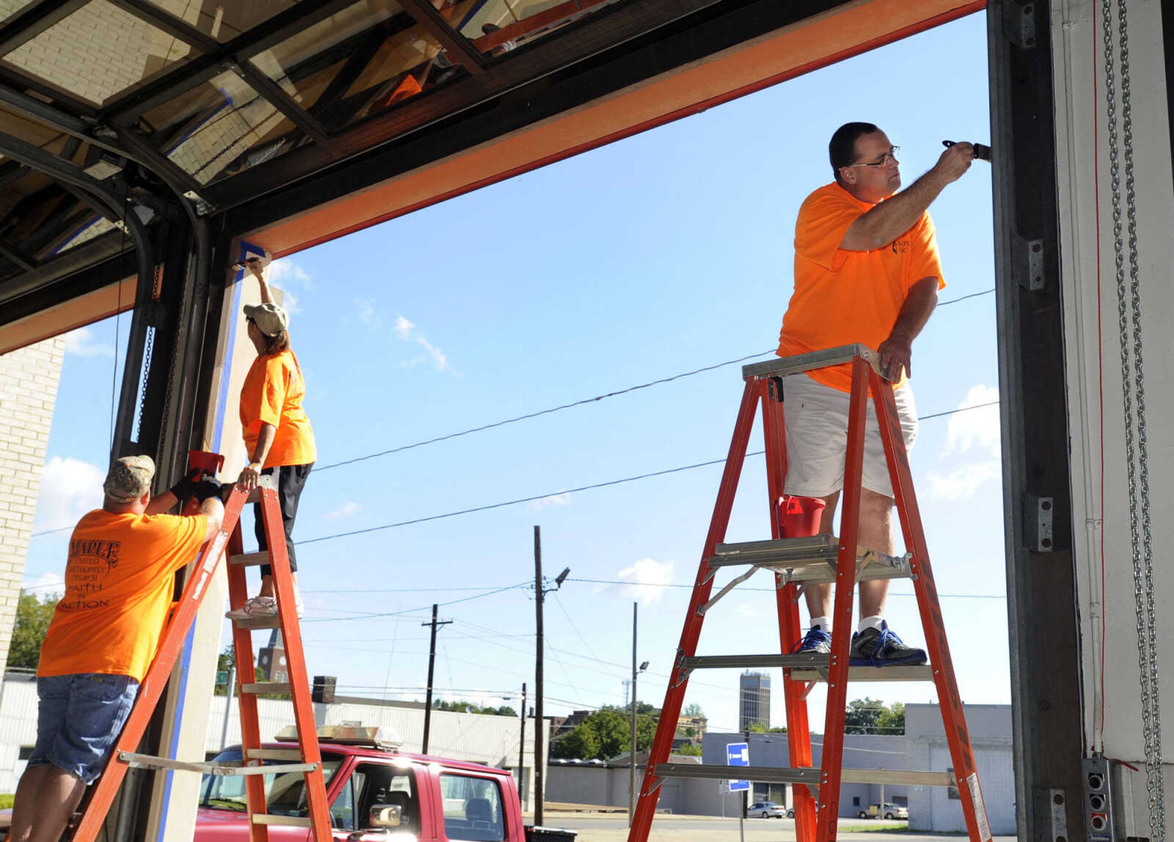 Chris Clifton, right, paints the door frame at Fire Station 1 with Robert Bertotripp and Robyn Morton.