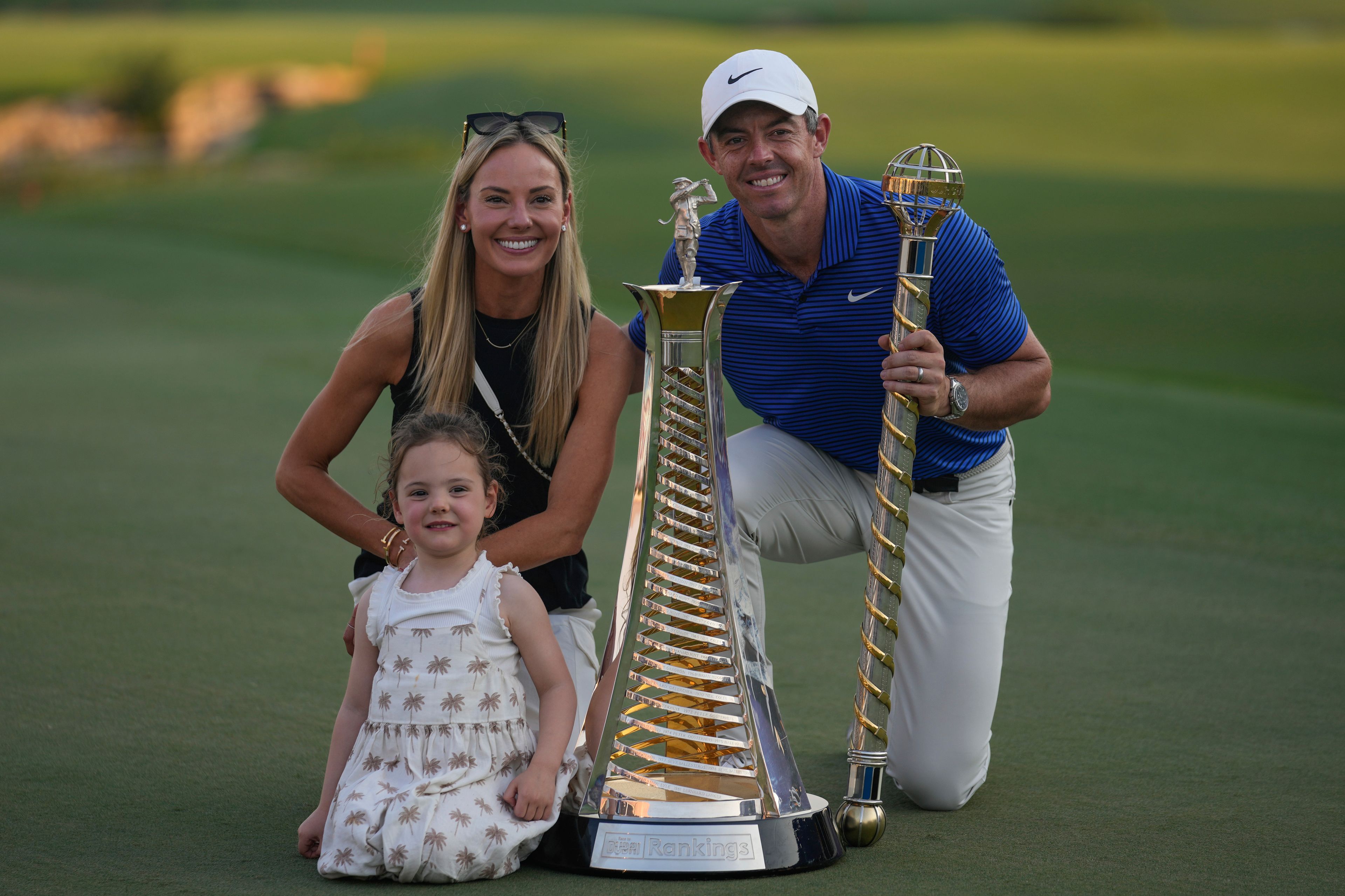 Rory McIlroy of Northern Ireland poses with his wife, Erica Stoll and Daughter, Poppy McIlroy alongside the trophies after winning the World Tour Golf Championship in Dubai, United Arab Emirates, Sunday, Nov. 17, 2024. (AP Photo/Altaf Qadri)