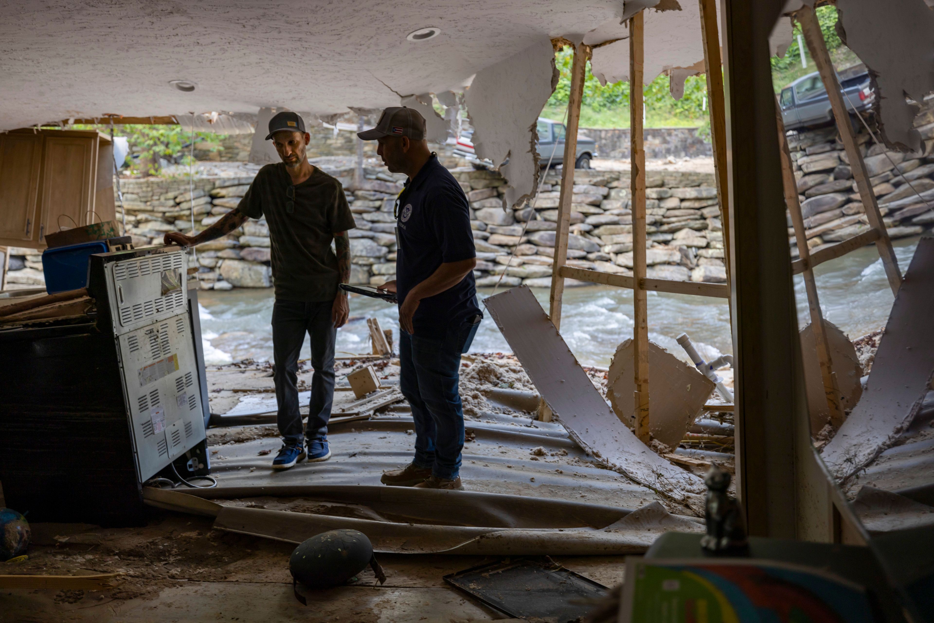 FEMA employee Jirau Alvaro works with Daniel Mancini, doing a report on the damage to his property on Sunday, Oct. 6, 2024 in rural Buncombe County, near Black Mountain, N.C. (Robert Willett/The News & Observer via AP)