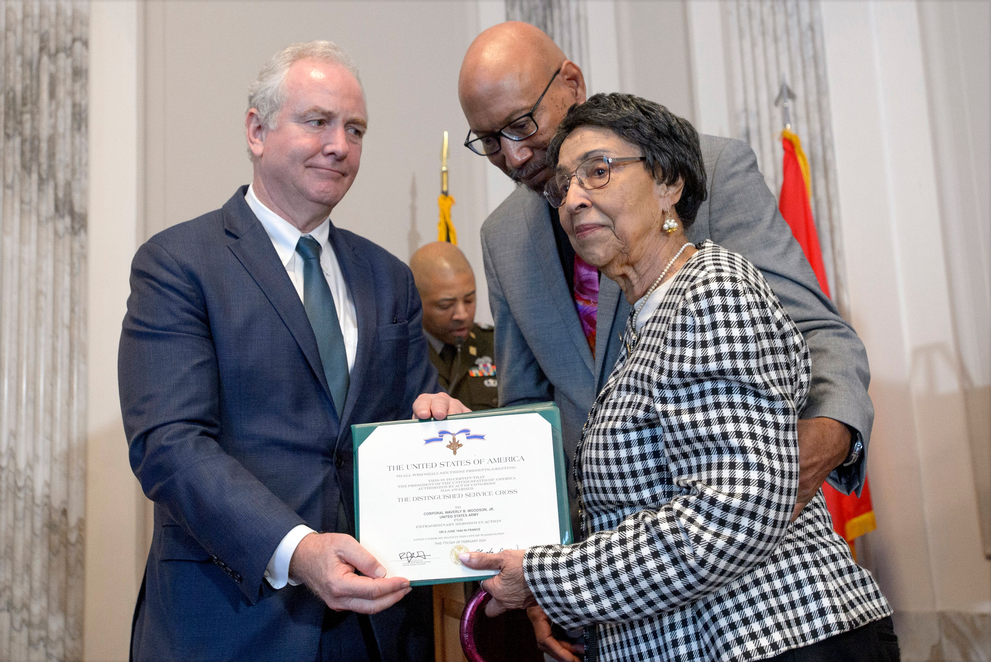 Sen. Chris Van Hollen, D-Md., left, presents the Distinguished Service Cross Award to Joann Woodson, center, and her son Steve Woodson, right, during a ceremony to posthumously award the Distinguished Service Cross to her husband U.S. Army Staff Sgt. Waverly Woodson, Jr., a medic who was part of the only Black combat unit to take part in the D-Day invasion of France during World War II, on Capitol Hill, in Washington, Tuesday, Sept. 24, 2024. (AP Photo/Rod Lamkey, Jr.)