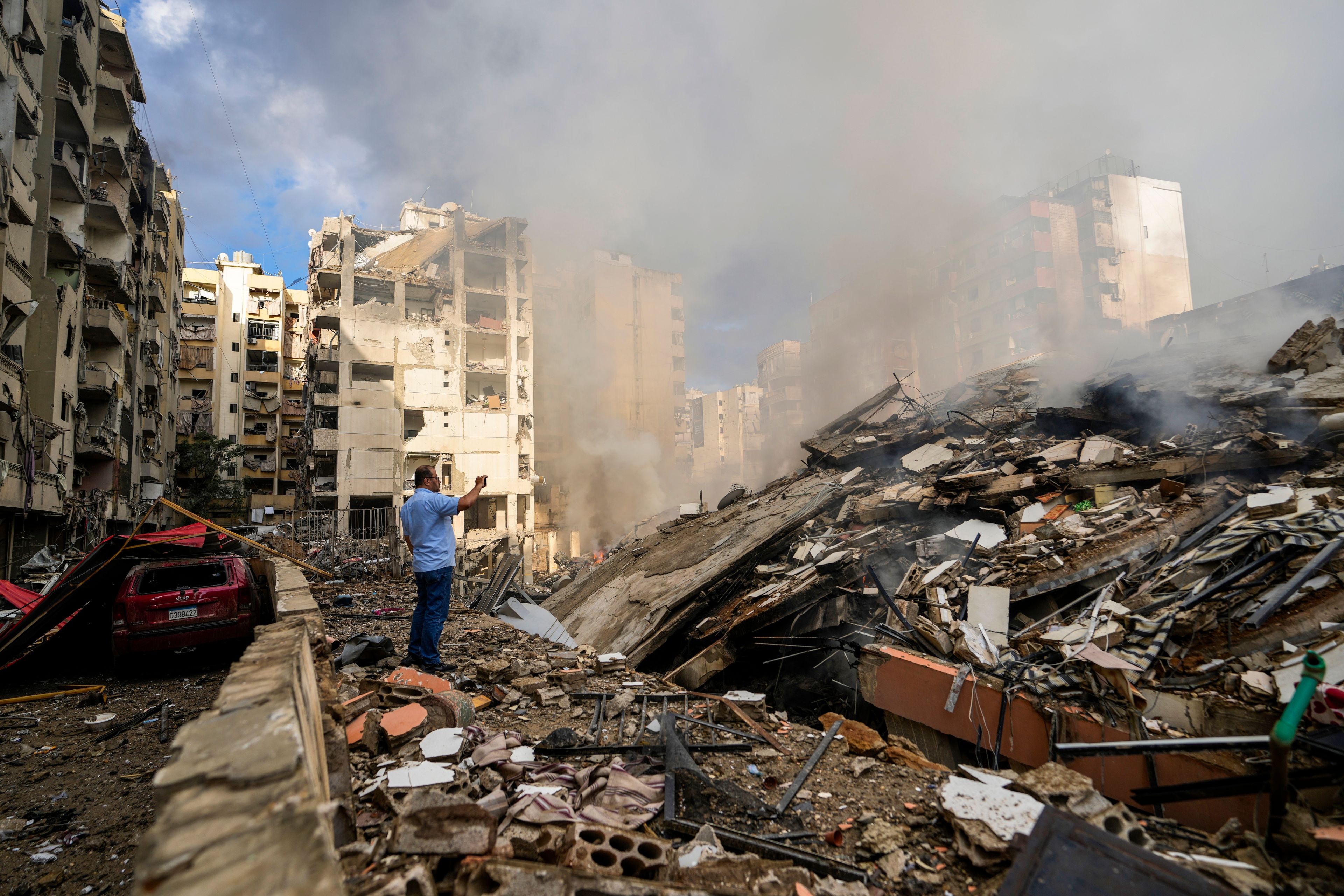 A man documents the damaged buildings at the site of an Israeli airstrike in Beirut's southern suburb, Lebanon, Tuesday, Oct. 1, 2024. (AP Photo/Hassan Ammar)