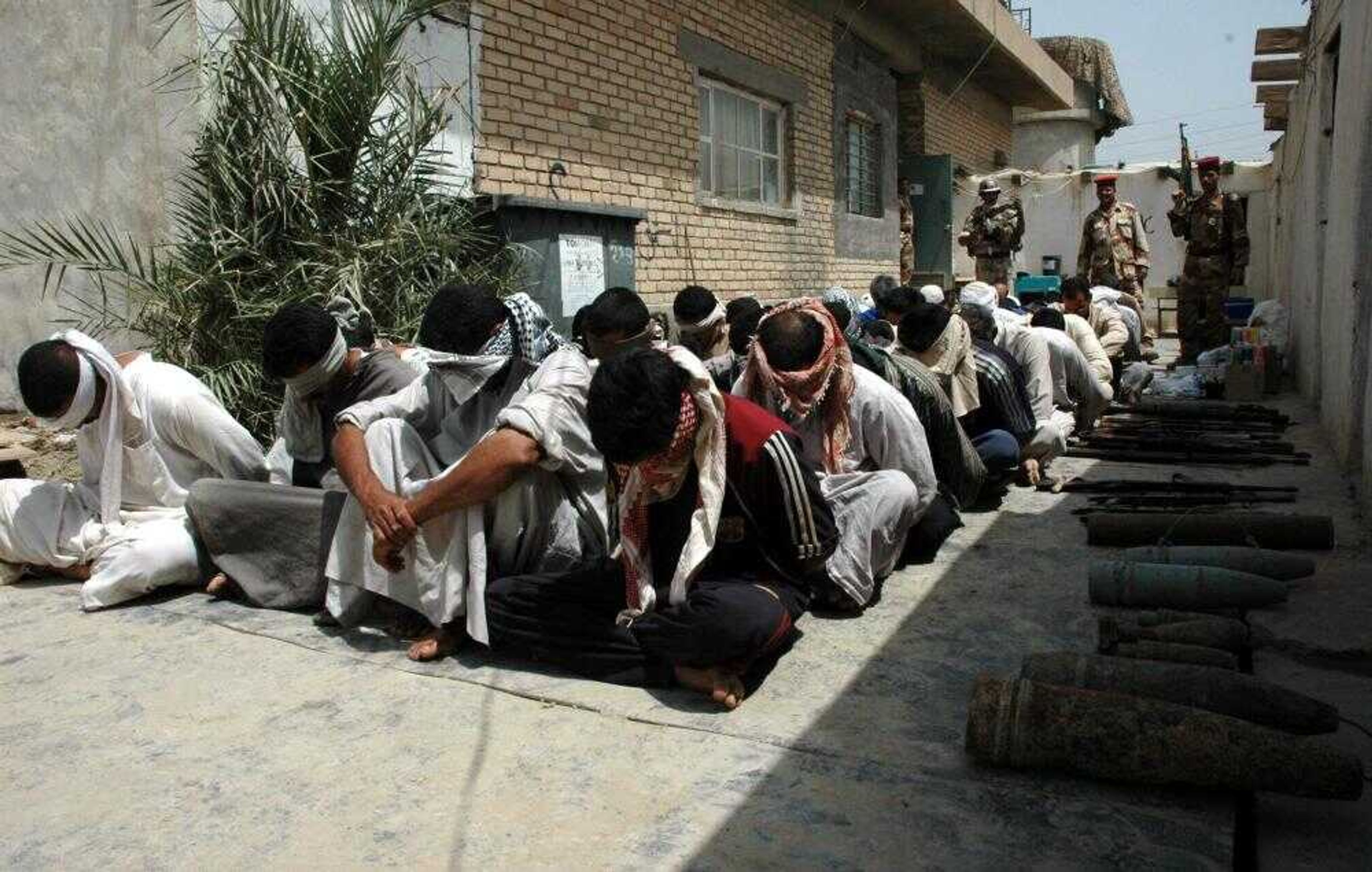 Blindfolded detainees sat on the ground Wednesday at the joint Iraqi U.S. military headquarters in Youssifiyah, 12 miles south of Baghdad, Iraq. Fifty-six suspected insurgents were arrested in a joint U.S. and Iraqi army raid in a village west of Youssifiyah. (Haidar Fatehi ~ Associated Press)