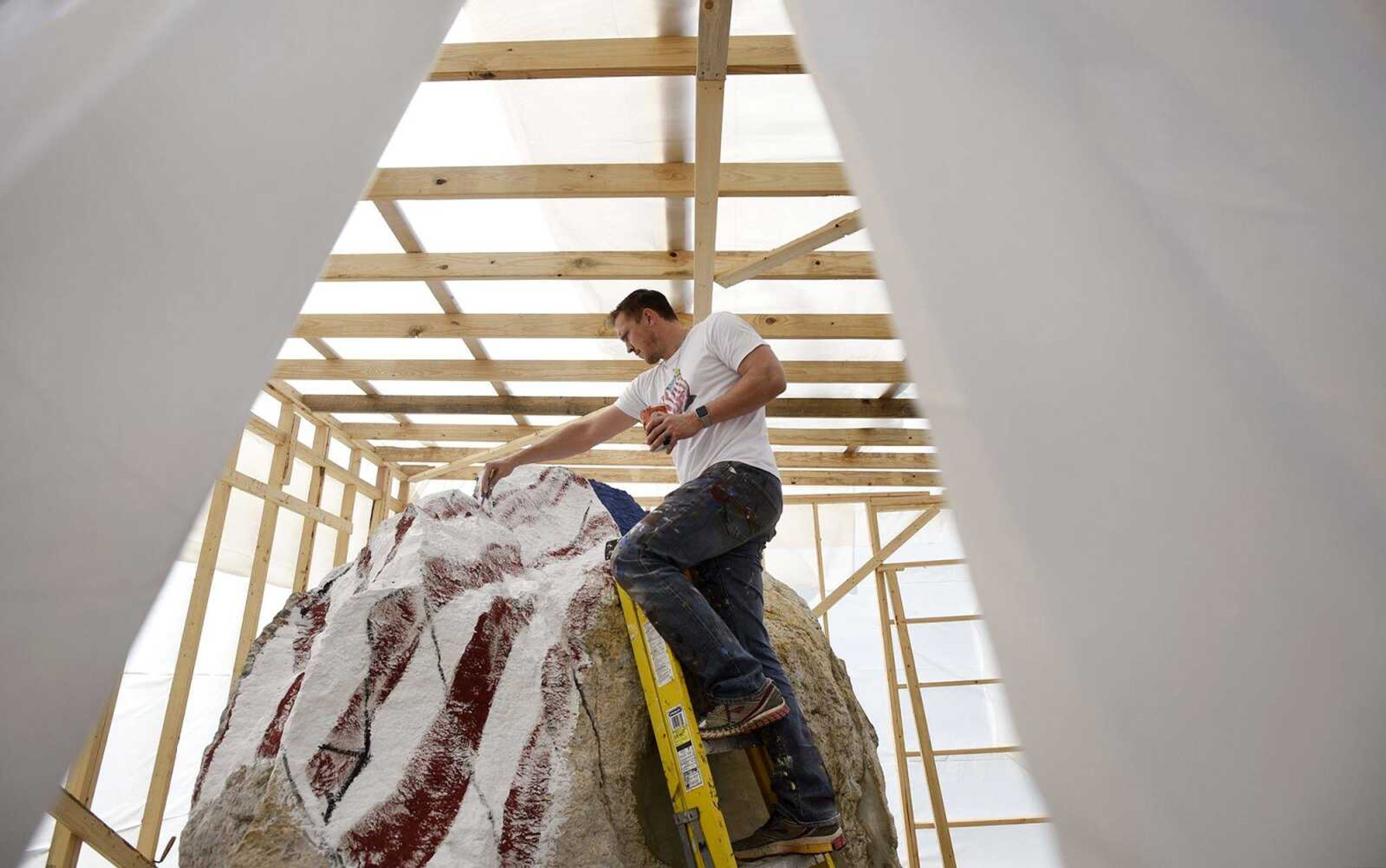 Iowa artist Ray "Bubba" Sorensen II, paints a patriotic tableau on 32-ton rock under a temporary shelter on Wednesday at Cape Girardeau County Park North. The rock is part of Veterans Plaza.