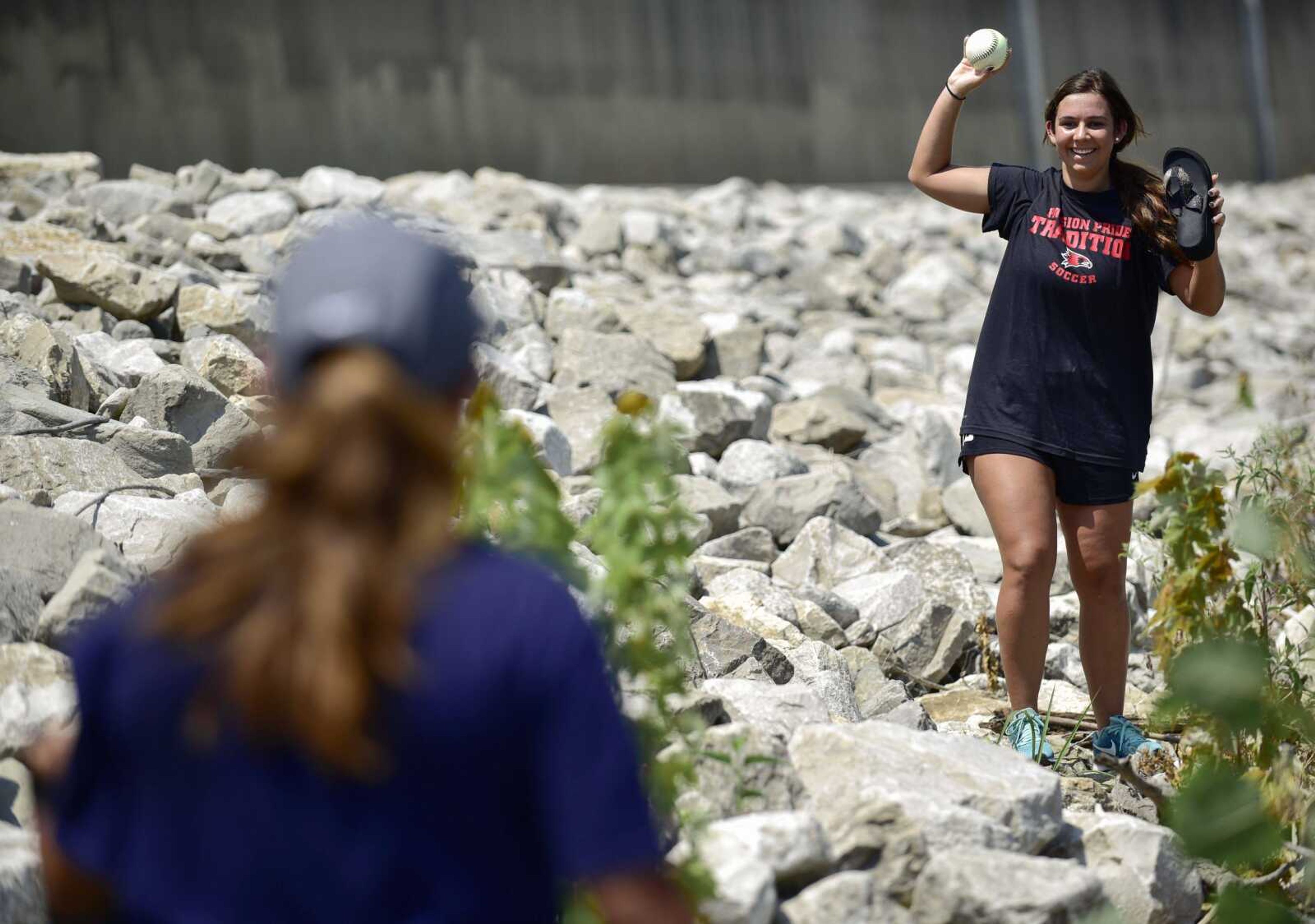 Southeast Missouri State University soccer player Jordan Nelson, right, tosses a littered softball to teammate Esmie Gonzales, left, while volunteering Friday at Riverfront Park in Cape Girardeau. Temperatures ranged in the low-90s during team cleanup, which aimed to beautify the riverfront for arrival of the American Queen steamboat, docking July 27, and the American Duchess, docking July 28.