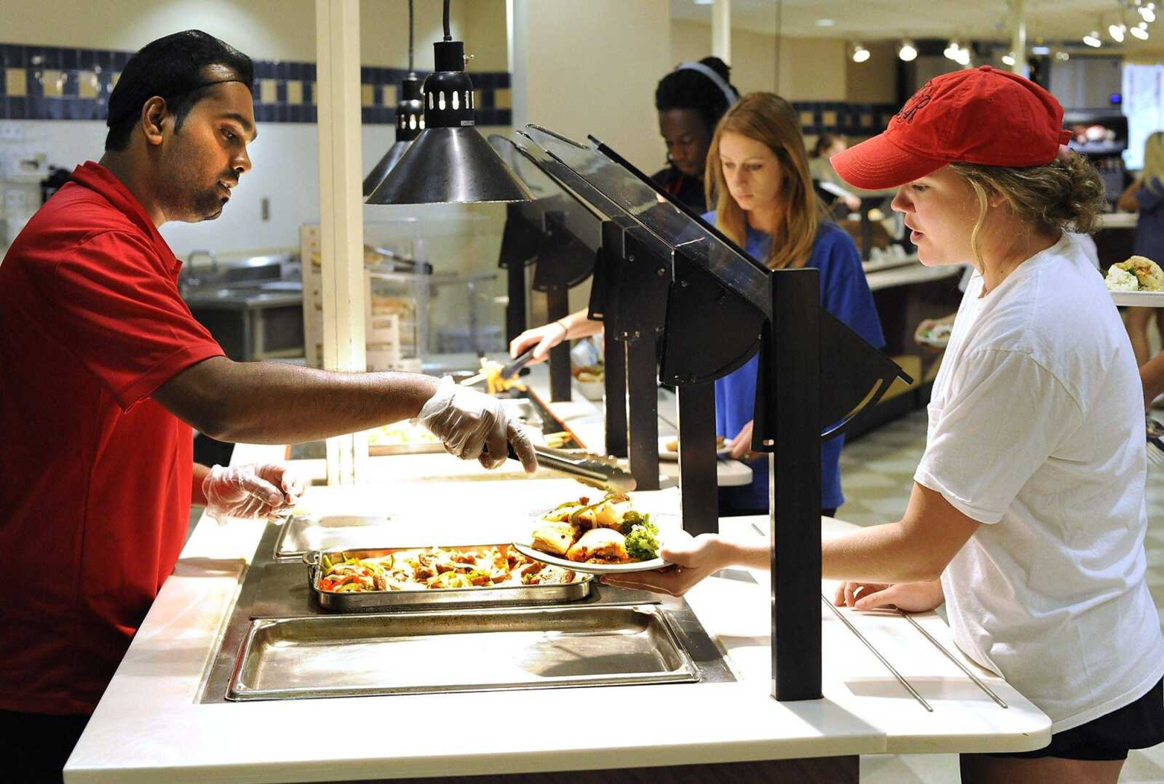 Chartwells server Kawsar Ali adds sausage, peppers and onions to Mattie Beussink's lunch plate Tuesday in the dining commons of Towers Complex at Southeast Missouri State University. (Fred Lynch)