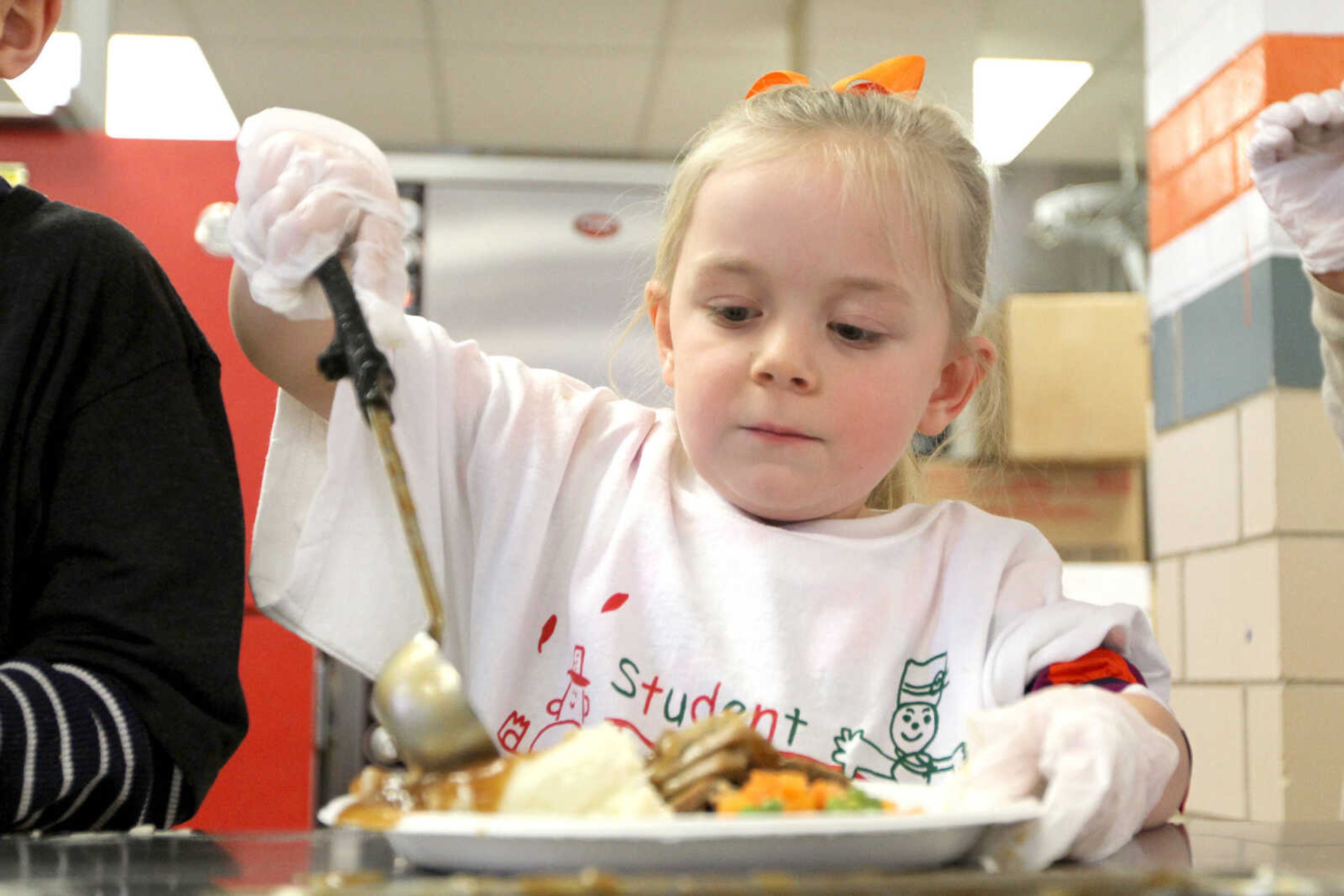 GLENN LANDBERG ~ glandberg@semissourian.com

Maya Stout serves gravy during the Student Santas Christmas dinner for families in need Thursday, Dec. 25, 2014 at Central Junior High School.