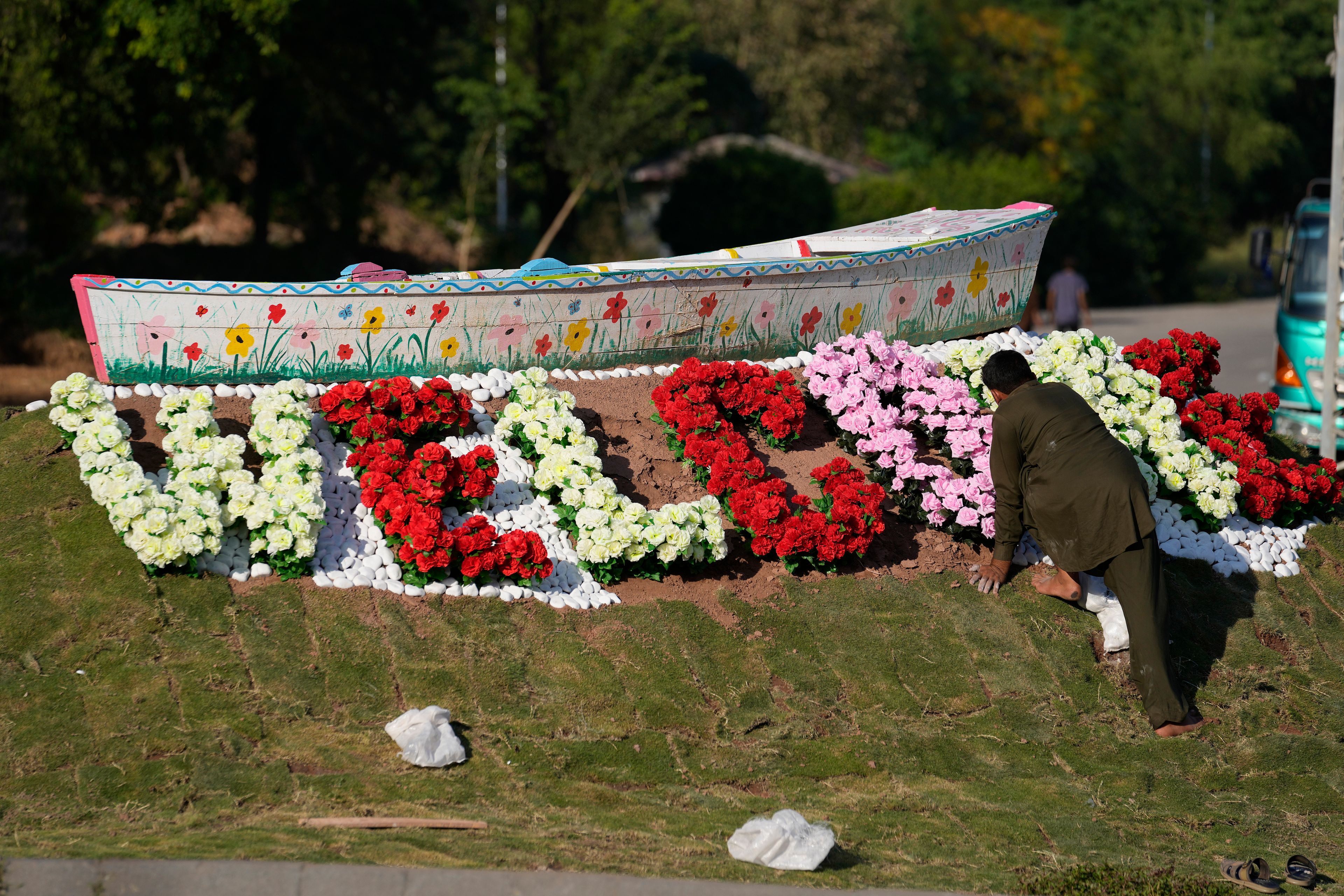 A worker gives the final touches to a floral artwork "welcome" display close to the venue of the upcoming Shanghai Cooperation Organization (SCO) summit in Islamabad, Pakistan, Sunday, Oct. 13, 2024. (AP Photo/Anjum Naveed)