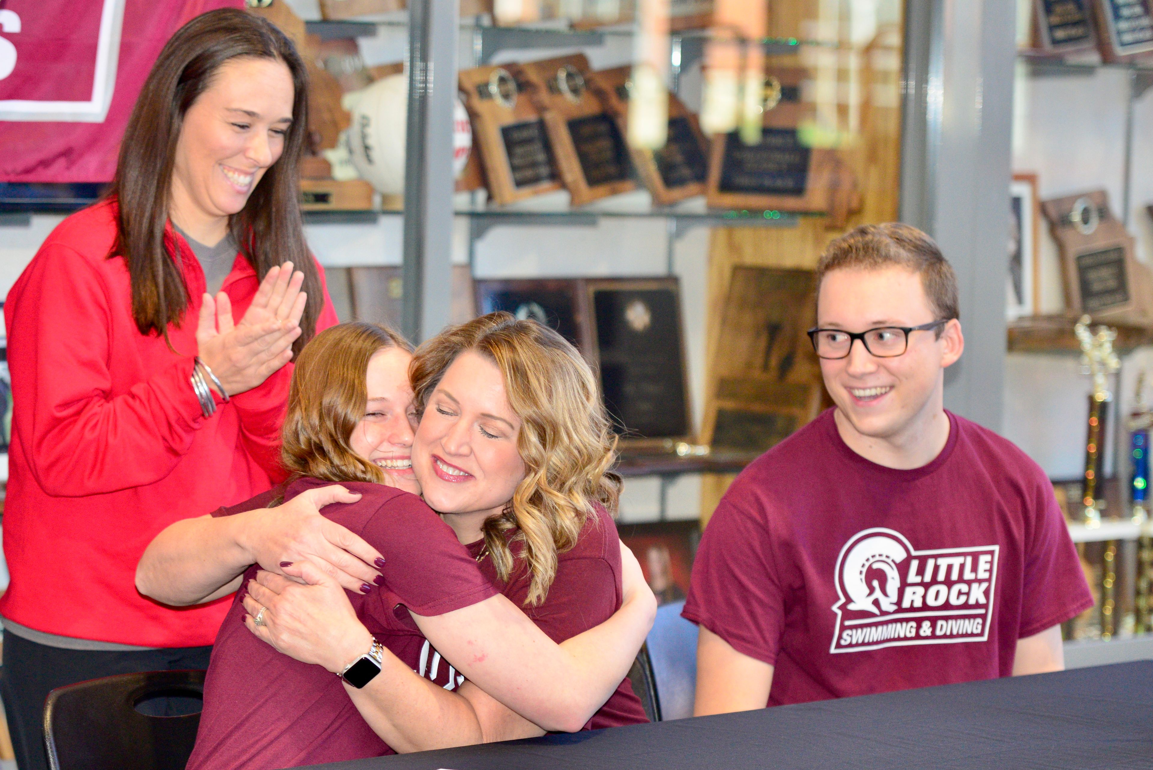 Jackson senior Ava Walters hugs her mother after signing her national letter of intent to swim collegiately for Little Rock on Thursday, Nov. 21, at Jackson High School in Jackson. Her older brother, Brayden Walters, right, is entering his first season as the head coach of the Jackson girls swimming team, while her father, Brad Walters, left, coaches the Notre Dame boys swimming team.