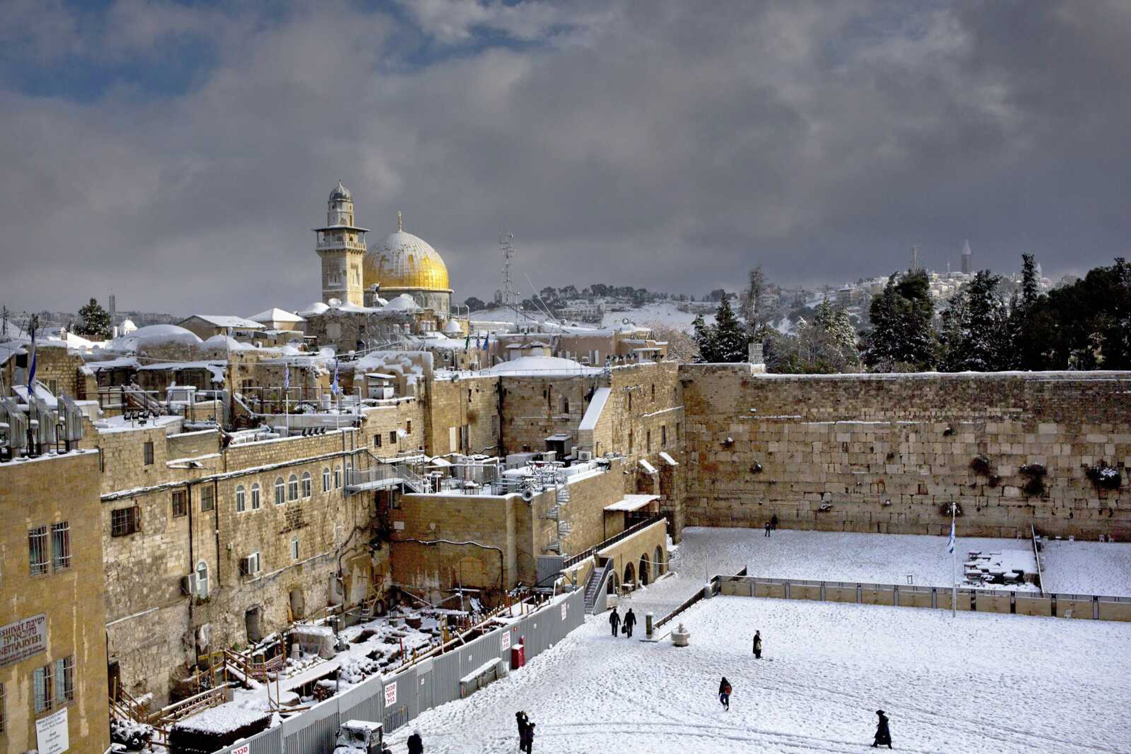 The Western Wall, right, and the gilded Dome of the Rock, among the holiest sites for Jews and Muslims, are covered in snow Dec. 13. Israeli police stormed a sensitive holy site in Jerusalem on Wednesday, firing tear gas to disperse a protest by Palestinian Muslim worshippers, officials said. (Associated Press file)