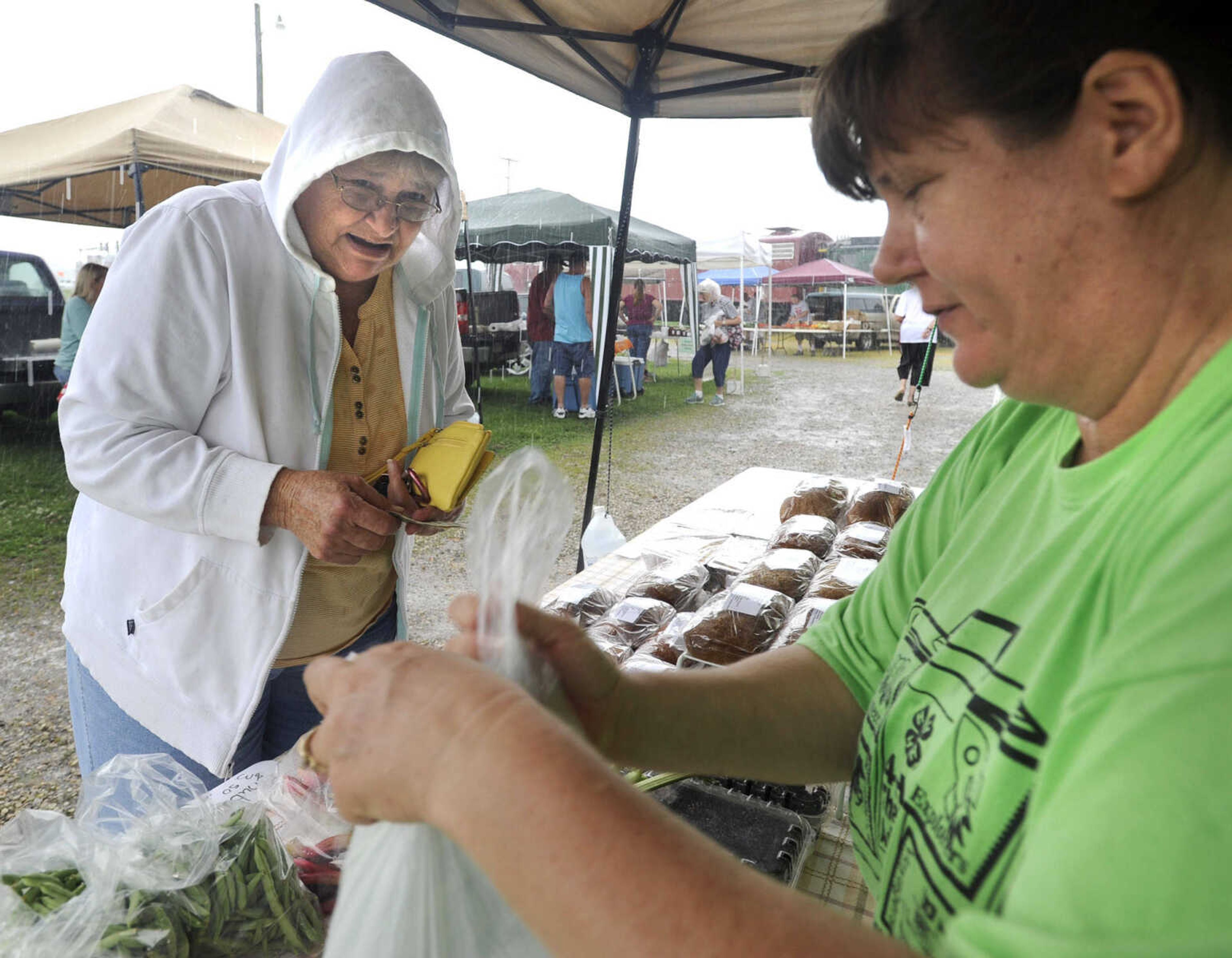 FRED LYNCH ~ flynch@semissourian.com
Betty Waller, left, of Jackson buys green beans and rhubarb from Laura Miesner of Frohna, Missouri as rain falls Tuesday, July 7, 2015 at the Jackson Farmer's Market in Jackson.