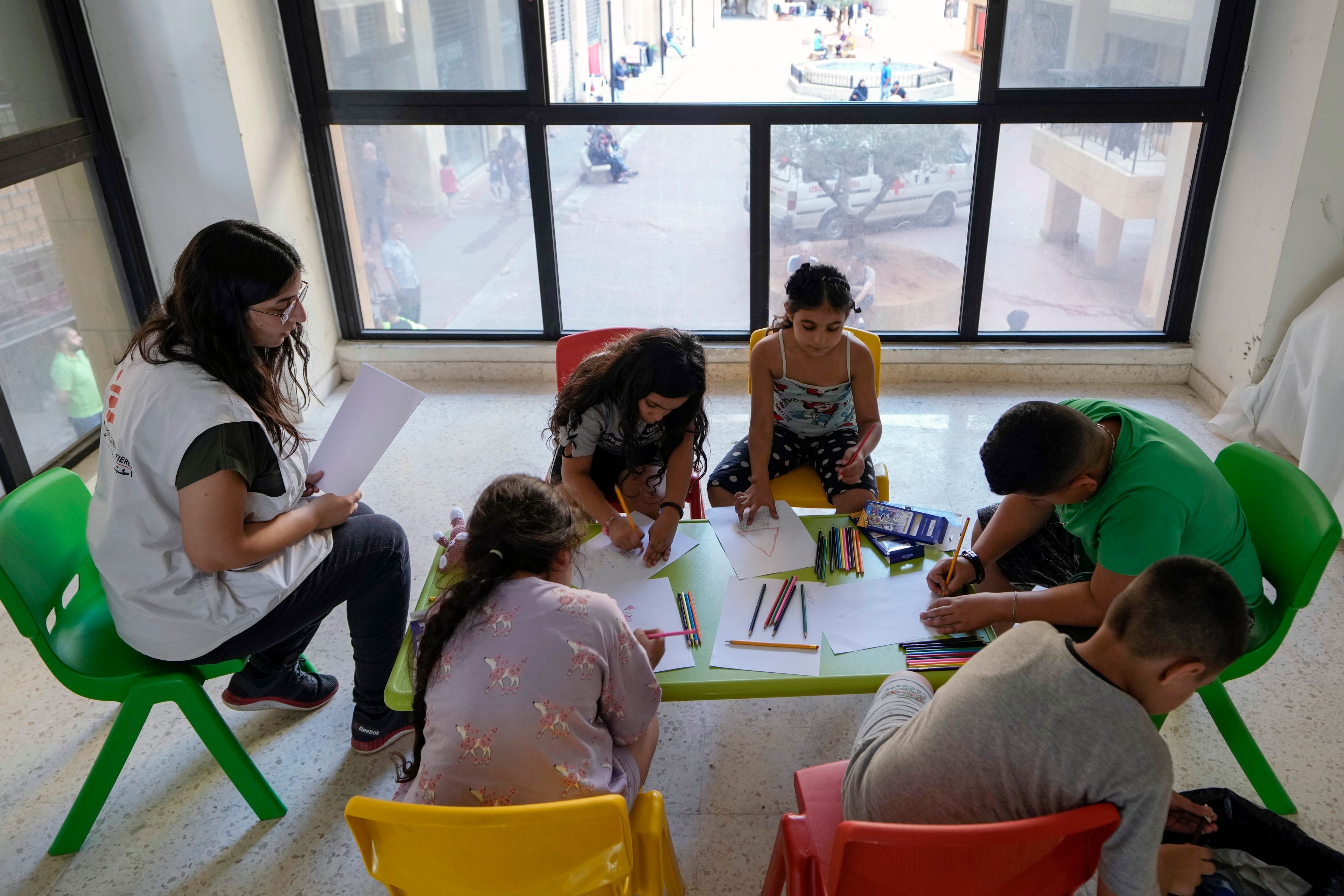 A Doctor's Without Borders counselor, left, talks to displaced children during a mental healthcare session in an empty building complex housing them, in Beirut, Lebanon, Wednesday, Oct. 9, 2024. (AP Photo/Bilal Hussein)