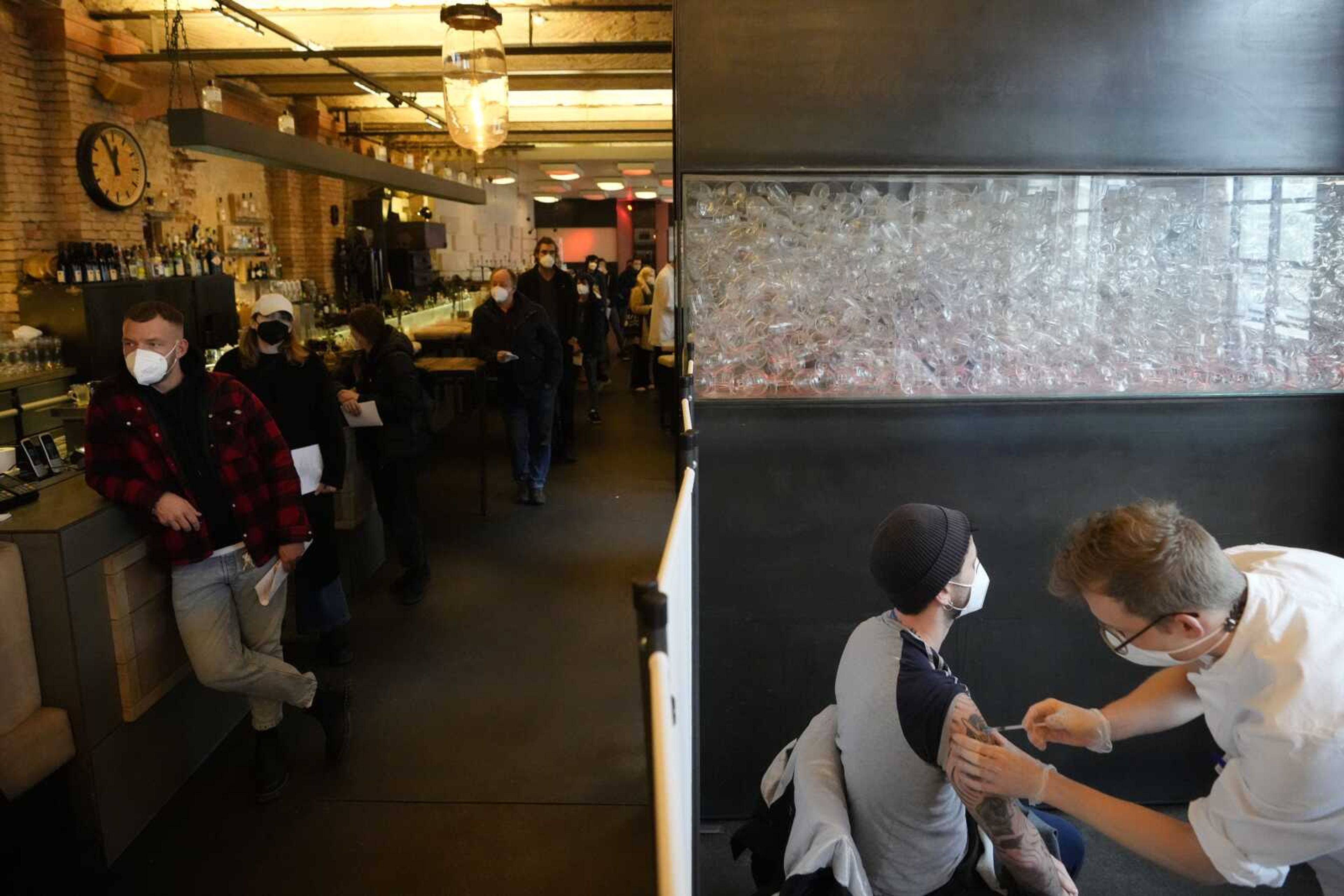 A doctor injects vaccination against the coronavirus and the COVID-19 disease to a man as other people line up for their vaccinations Jan. 3 inside the Sage Beach Bar and Restaurant in Berlin.