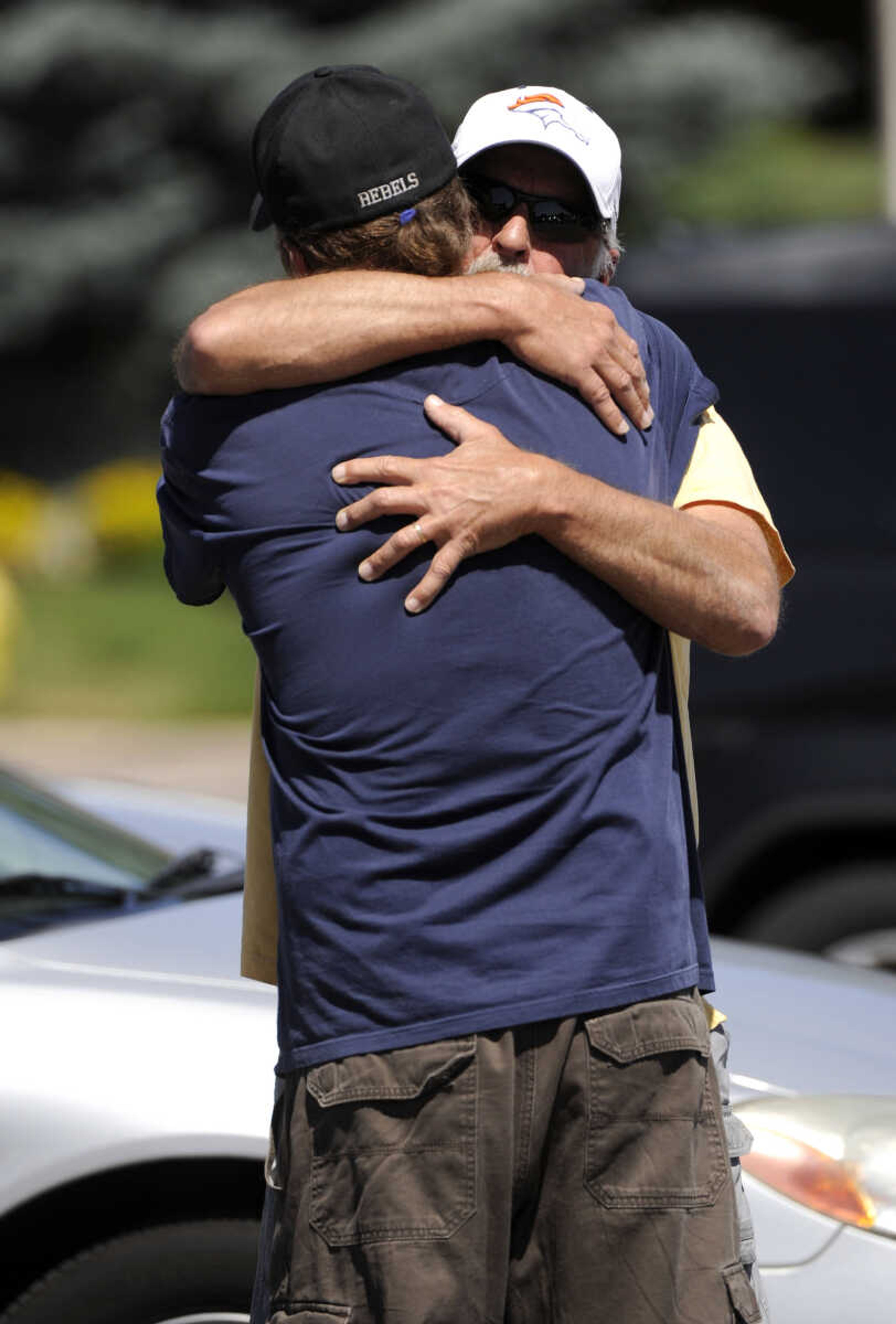 Two men hug outside Gateway High School in Aurora, Colo., where witnesses are being interviewed by authorities Friday, July 20, 2012. A  gunman wearing a gas mask set off an unknown gas and fired into the crowded movie theater killing 12 people and injuring dozens, authorities said.  The suspect is identified as 24-year-old James Holmes.(AP Photo/The Denver Post, Craig F. Walker) TV, INTERNET AND MAGAZINES CALL FOR RATES AND TERMS