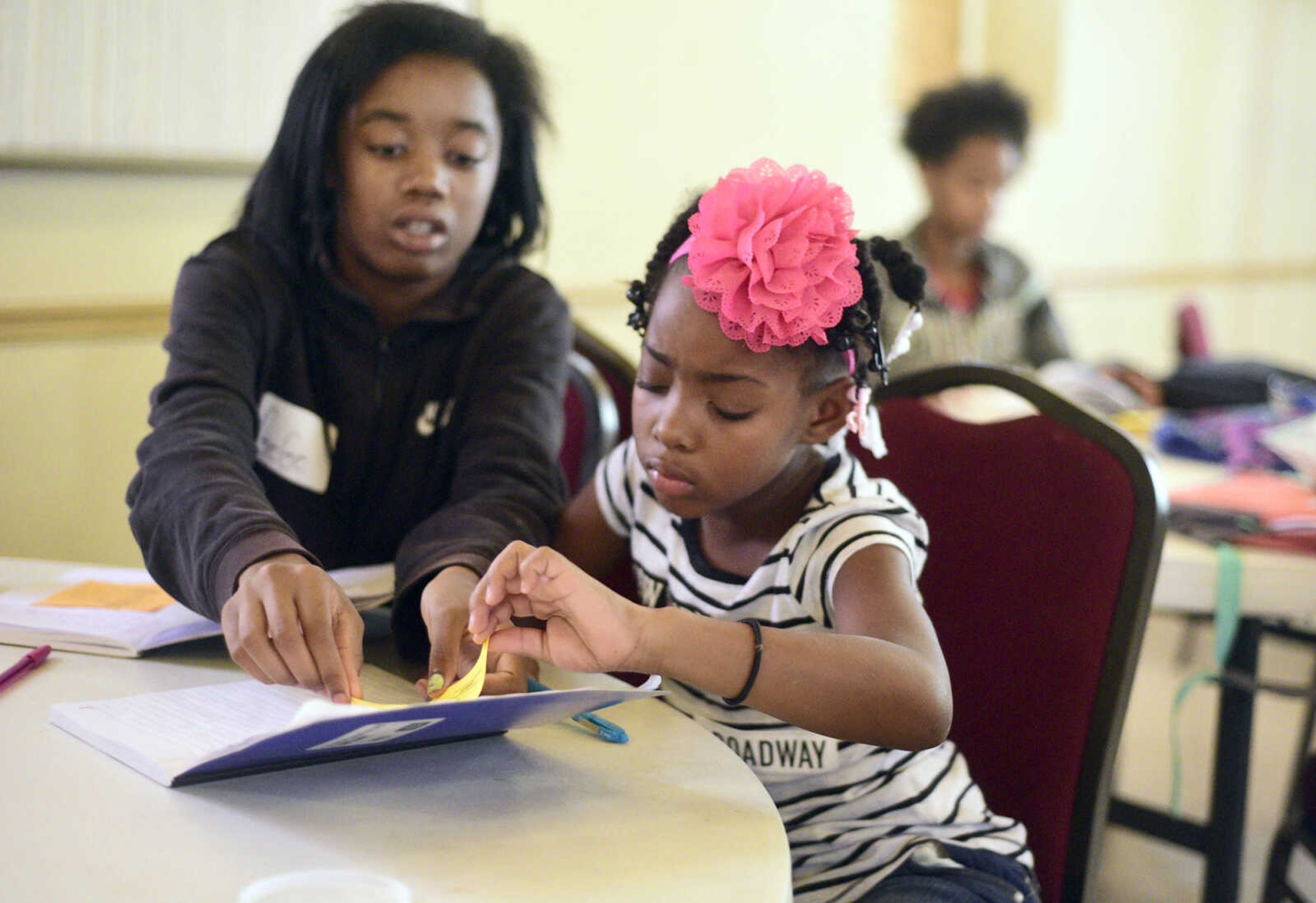 GeGe Green, left, helps Kamajah Hamilton glue a piece of paper in her journal on Monday, Aug. 14, 2017, during the Salvation Army's after school program at The Bridge Outreach Center in Cape Girardeau.