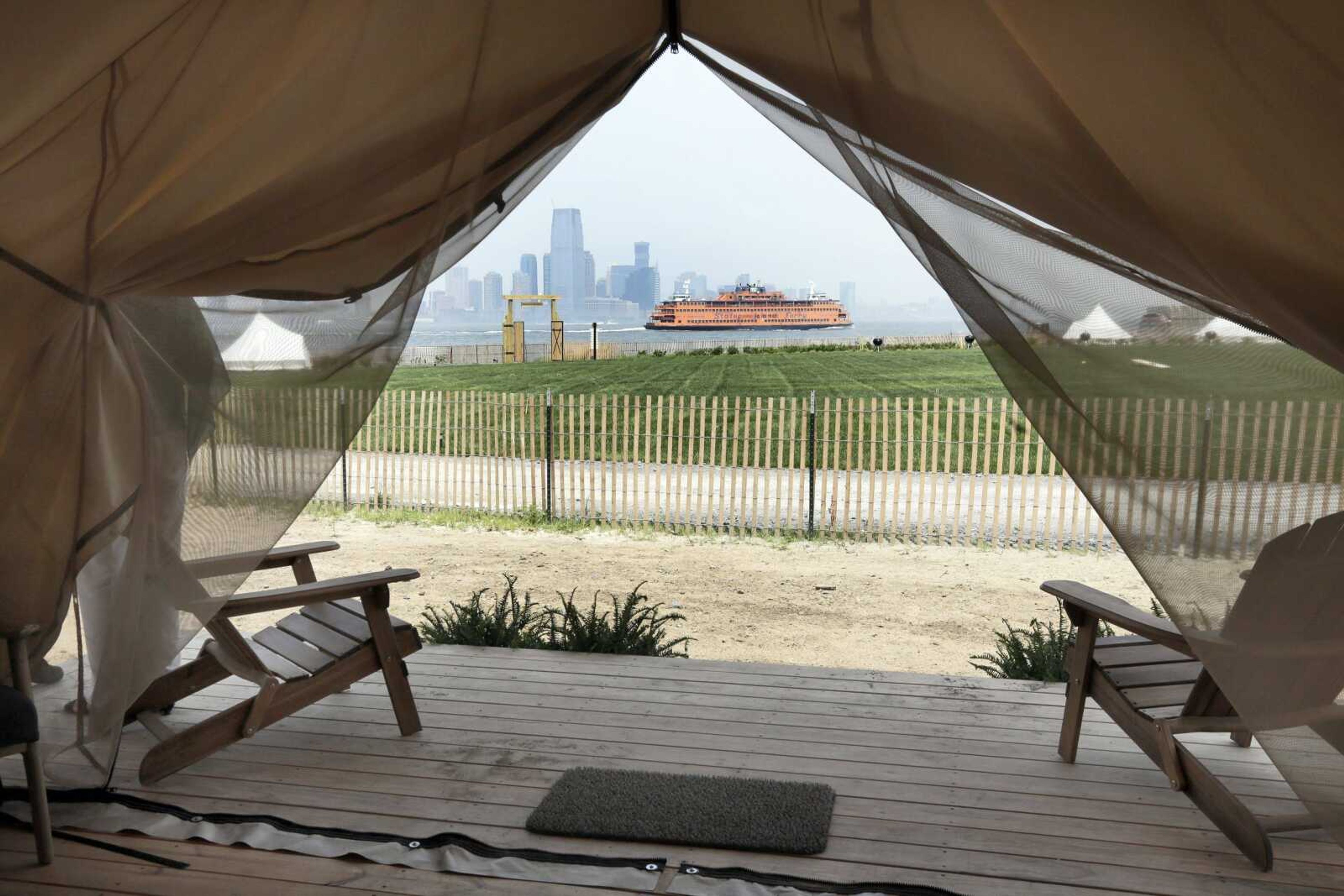 A Staten Island Ferry and several Journey Tents are seen Tuesday from one of Collective Retreats' Summit Tents on Governors Island in New York harbor. Guests staying at the Collective Retreats campsite on Governor's Island stay in furnished, luxury tents costing as much as a Manhattan hotel room.